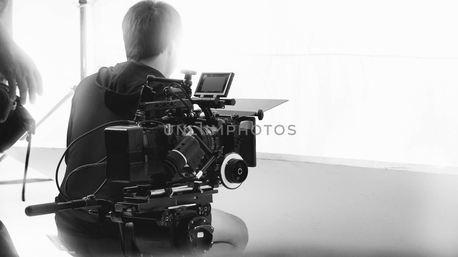 Behind video camera that recording online commercial or web film movie in the big studio production with professional equipment such as high resolution cam and monitors and LED light with crew team set