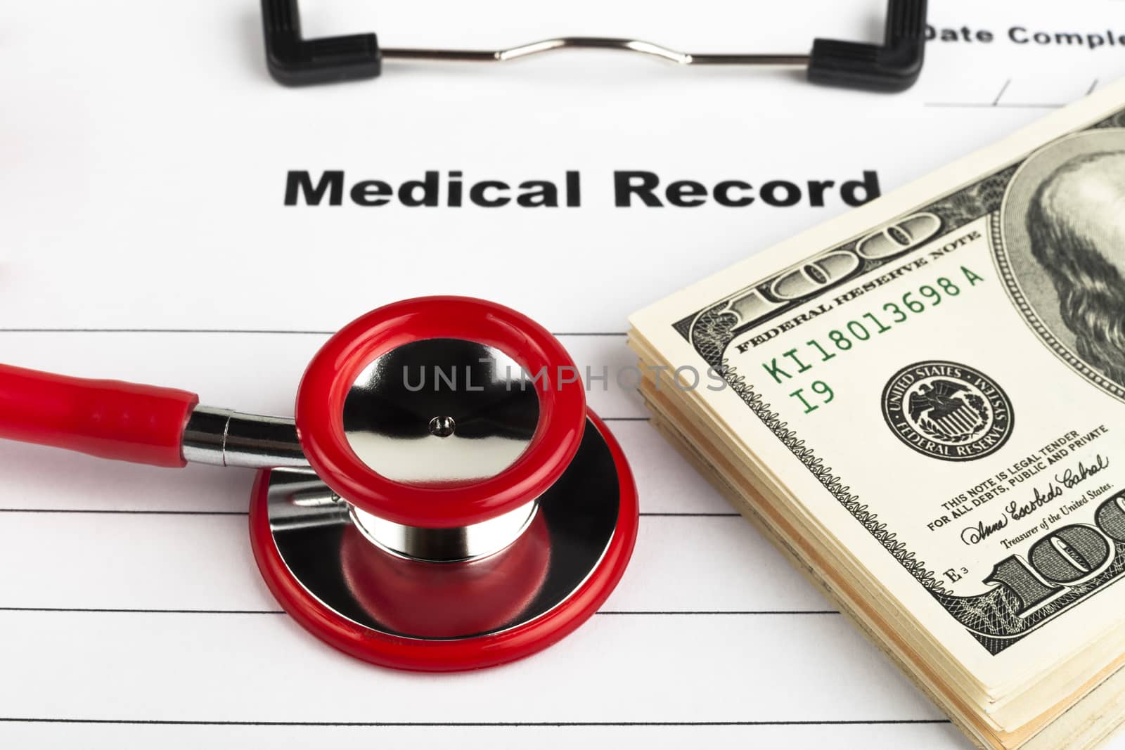 Money on a medical record clipboard with a red stethoscope isolated on white background