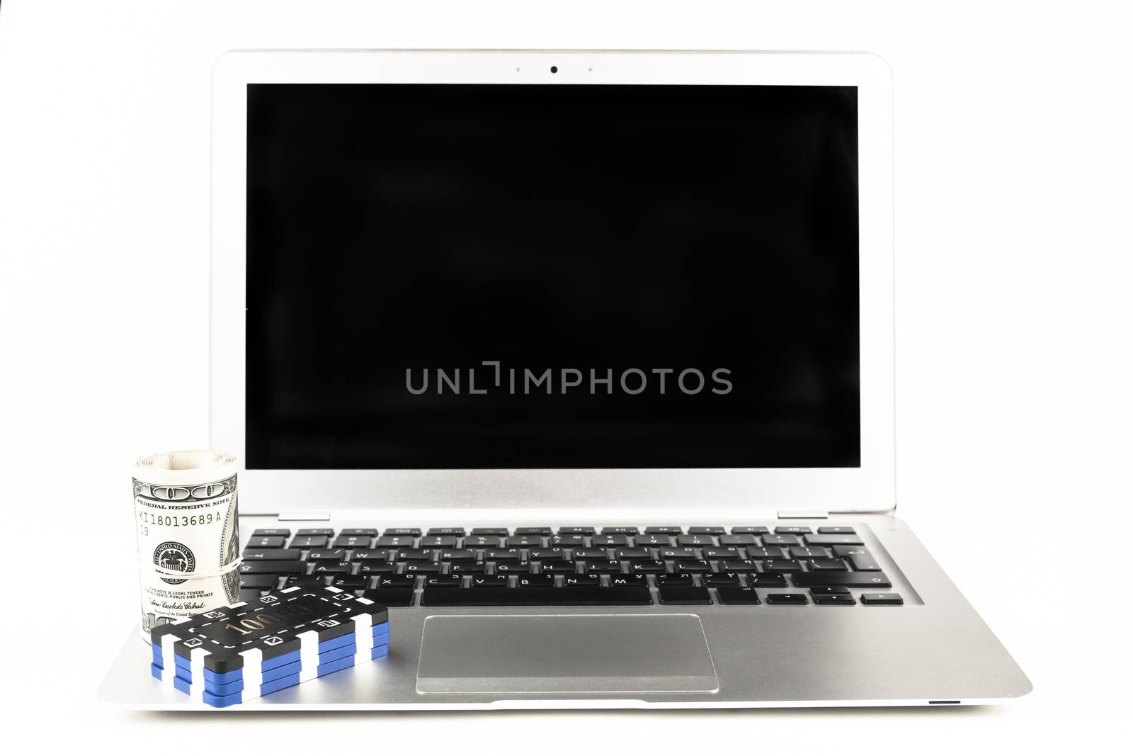 Dollars and casino chips on a silver laptop isolated on white background