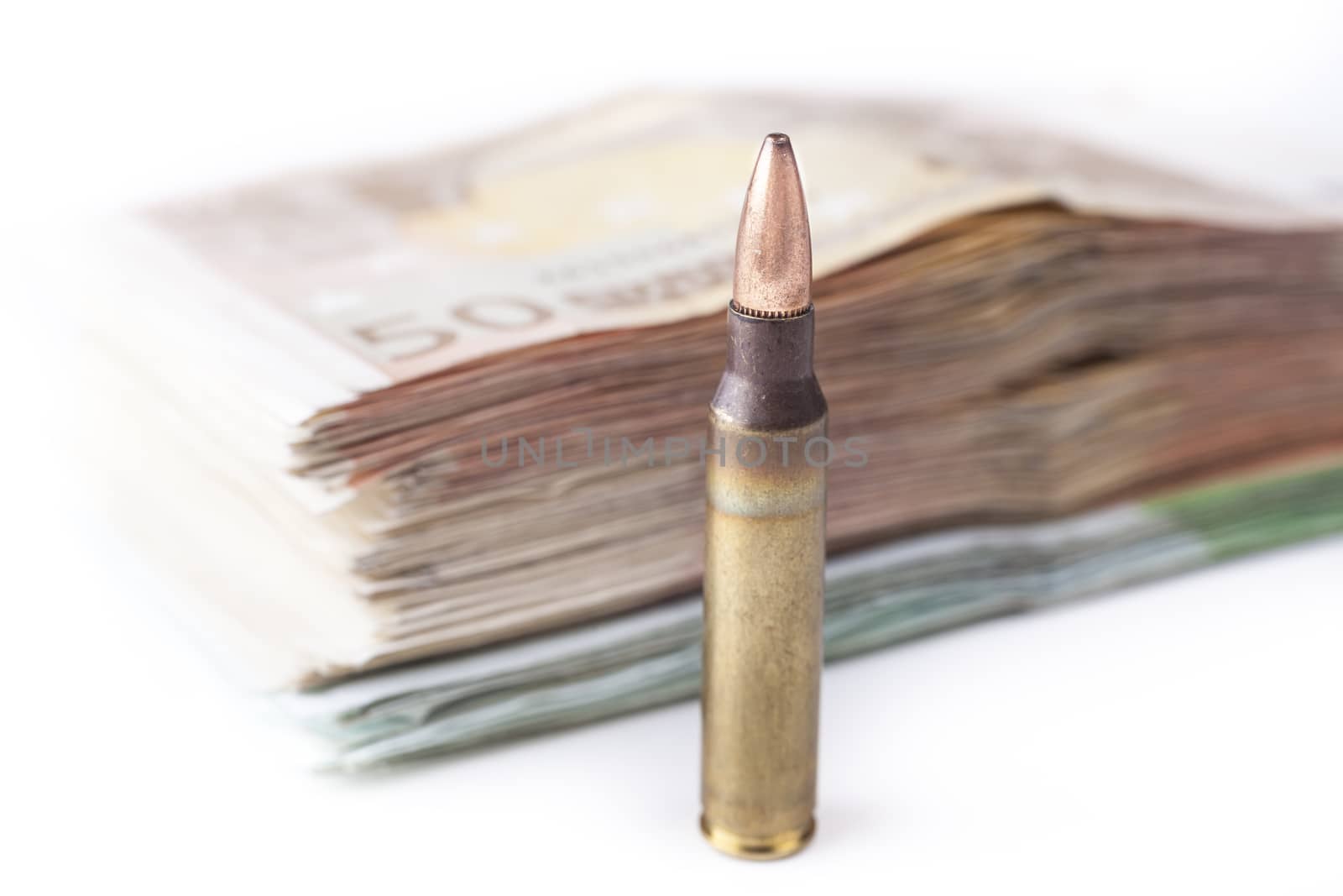 Single rifle bullet closeup with a pile of euro banknotes in the background isolated on white
