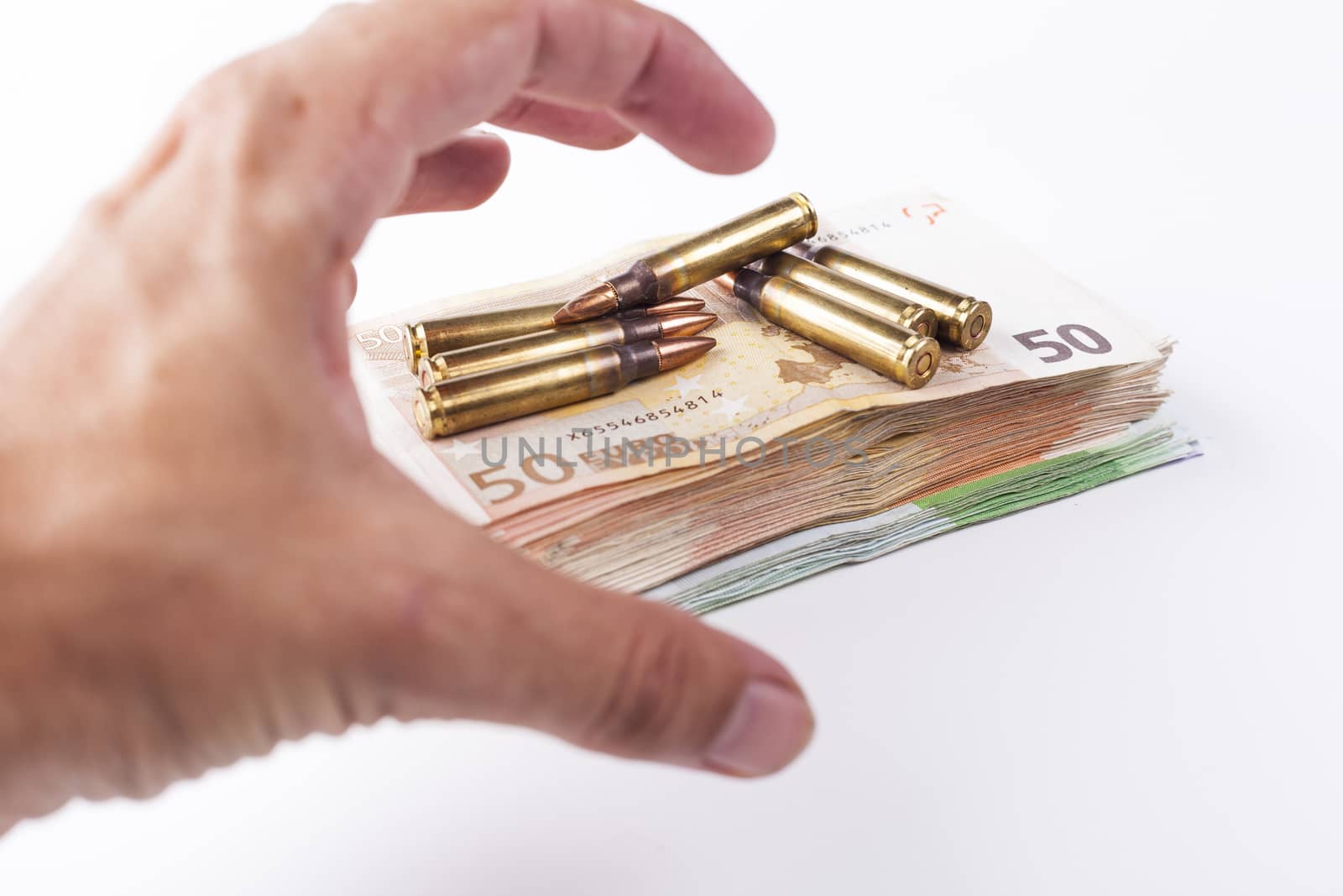 Hand grabbing a pil of bullets with euro banknotes isolated on white background