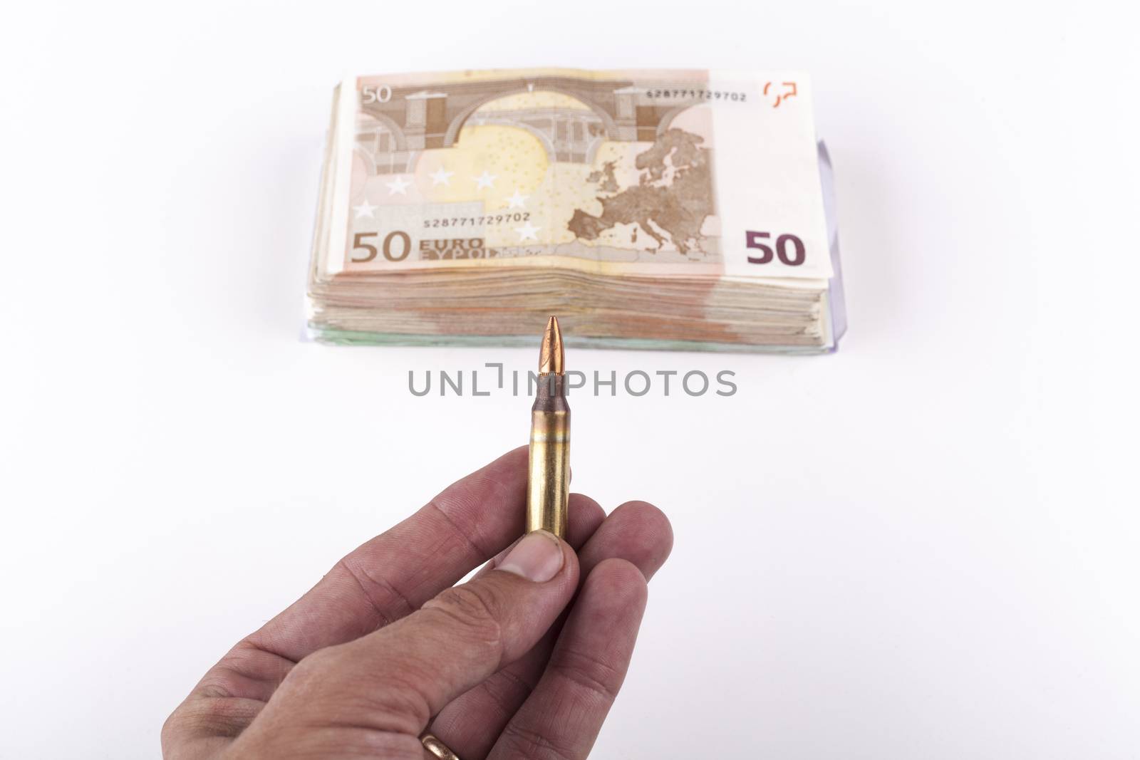 Man hand holding a rifle bullet with a bunch of euro banknotes isolated on white background