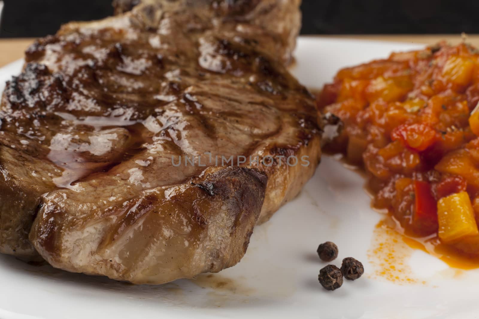 Grilled pork steak with vegetable garnish and some black peppers