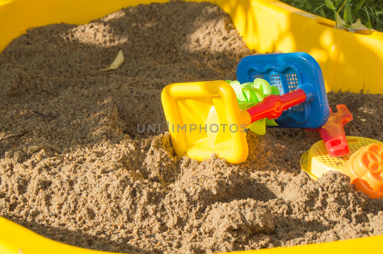 set of colored plastic toys on the sand, children's sandbox in summer Sunny day.