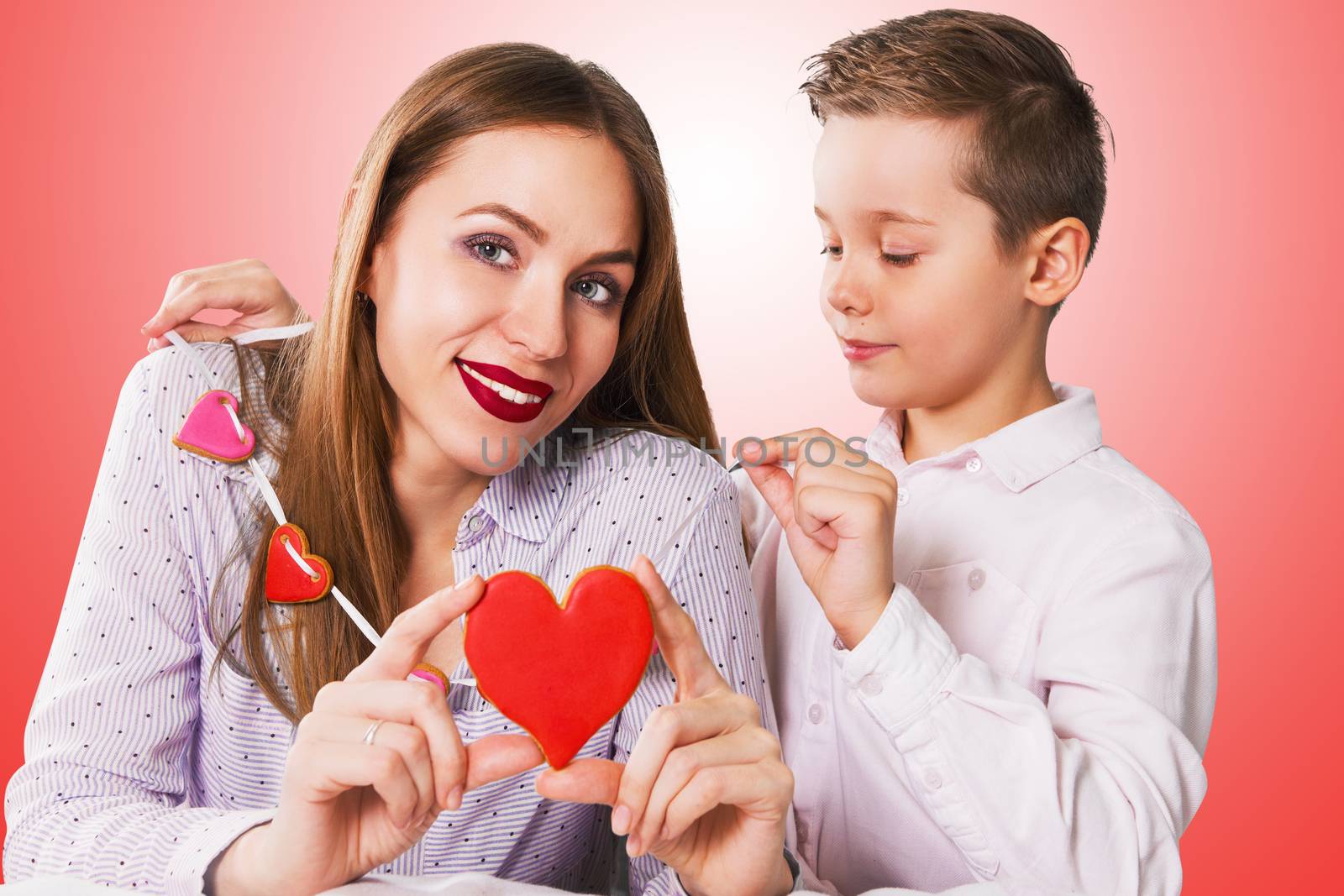 Happy Valentines Day or Mother day. Young boy and mum celebrate with gingerbread heart cookies on a stick.