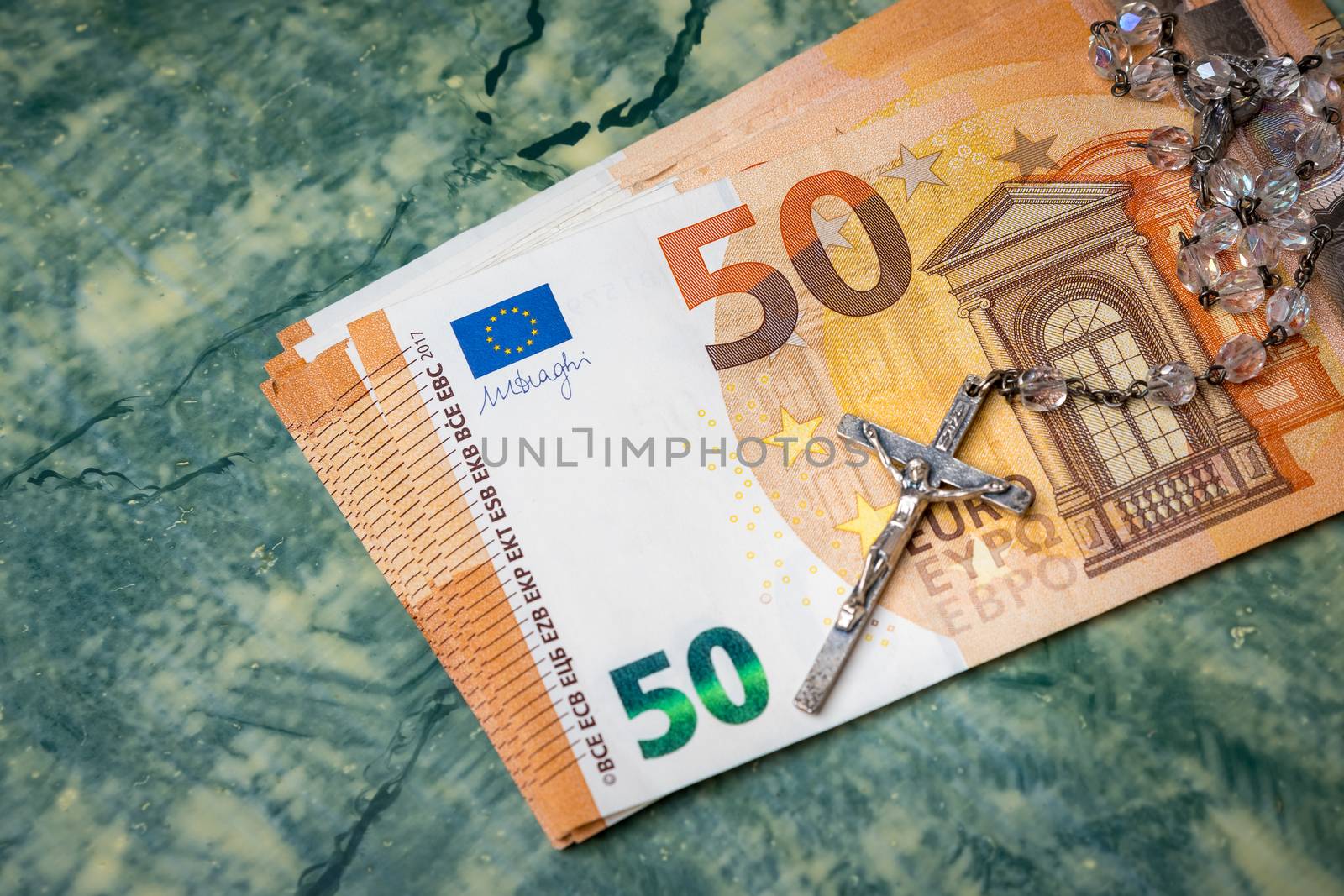 Silver  rosary and euro money on green table,concept photo.