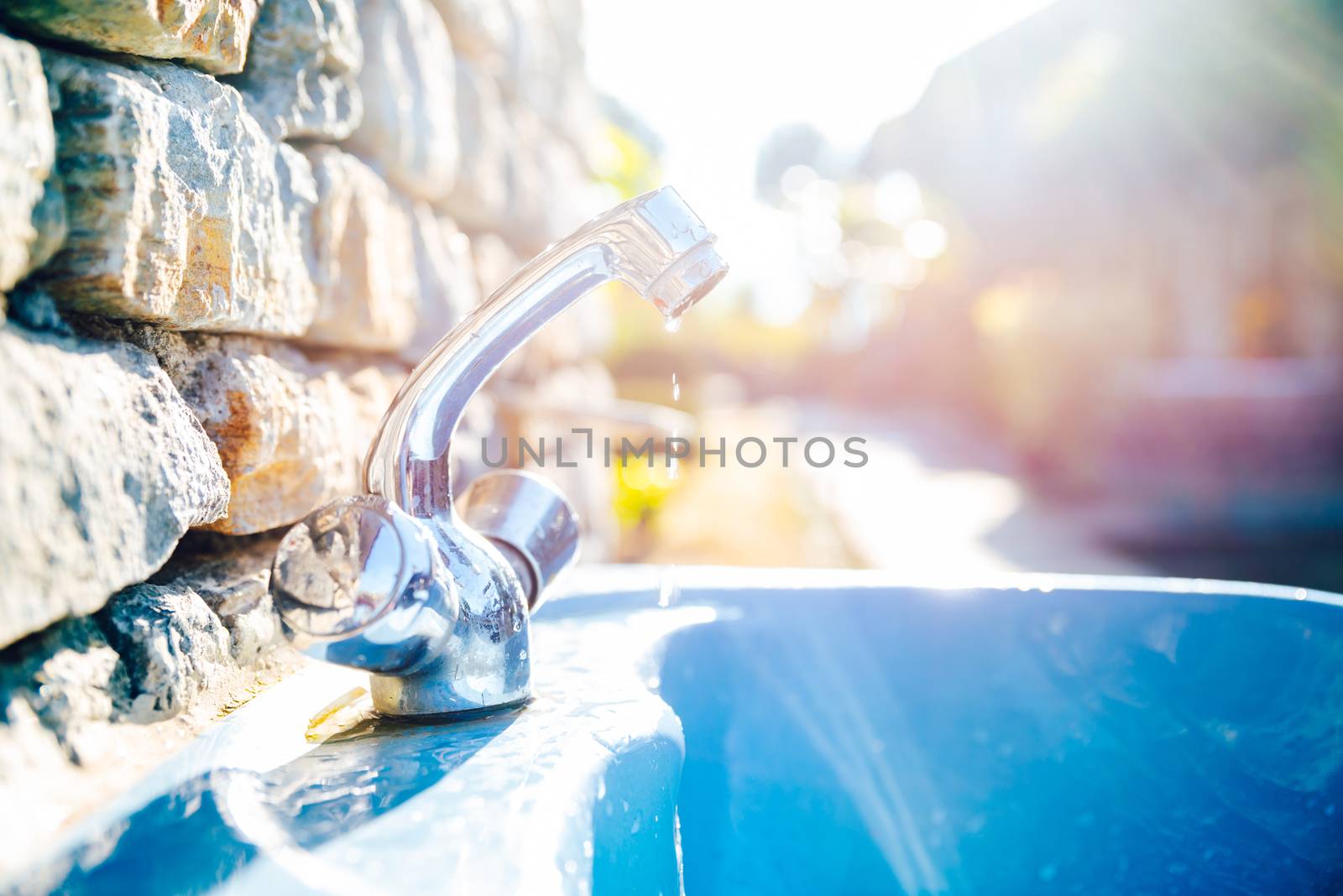 Outdoor washbasin in a garden, water dripping from tap. Waste concept.