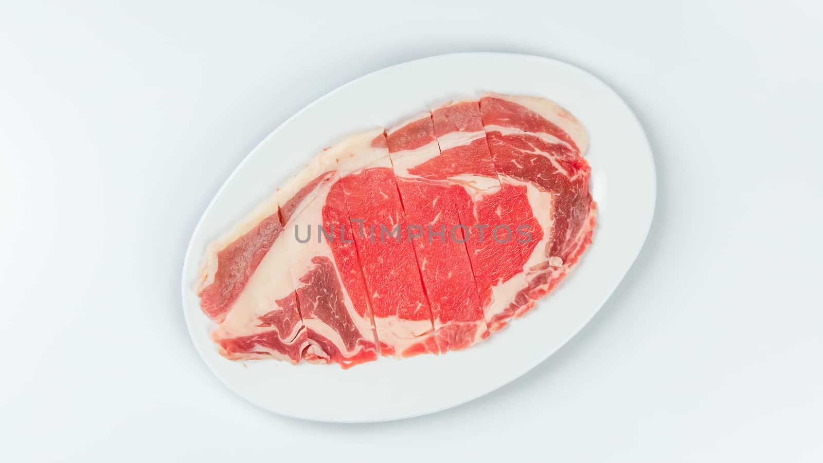 Top view of some raw beef on a plate over white background