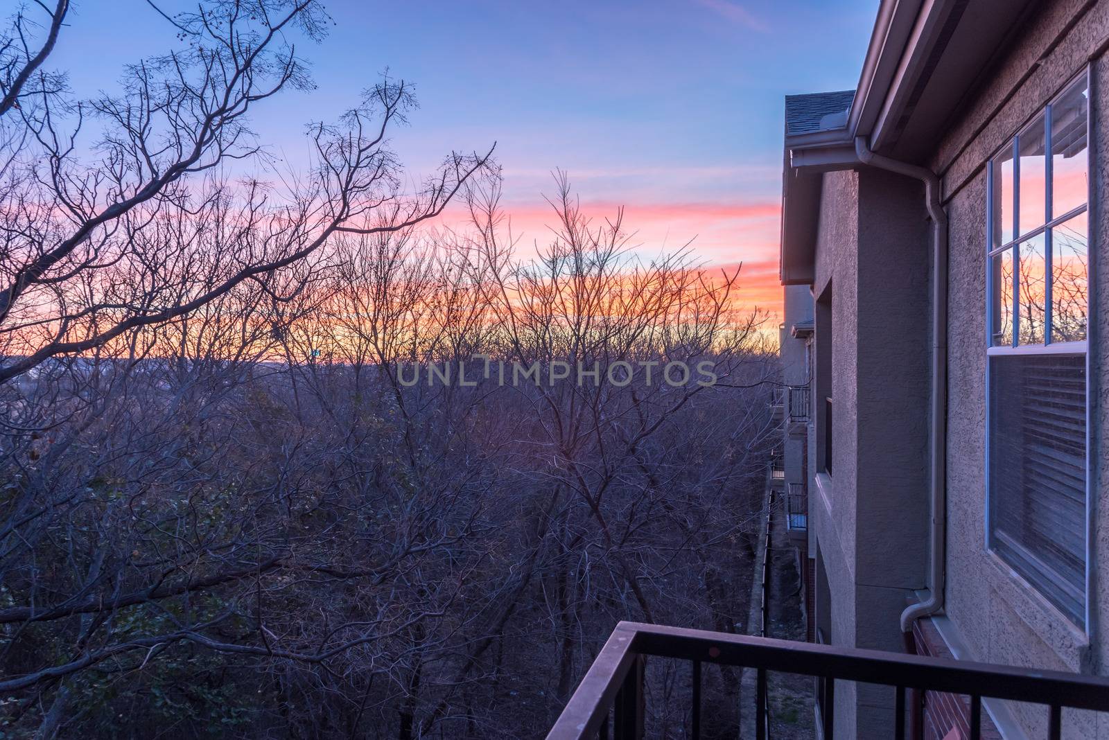 Park side apartment complex balcony during winter sunrise with dramatic clouds by trongnguyen