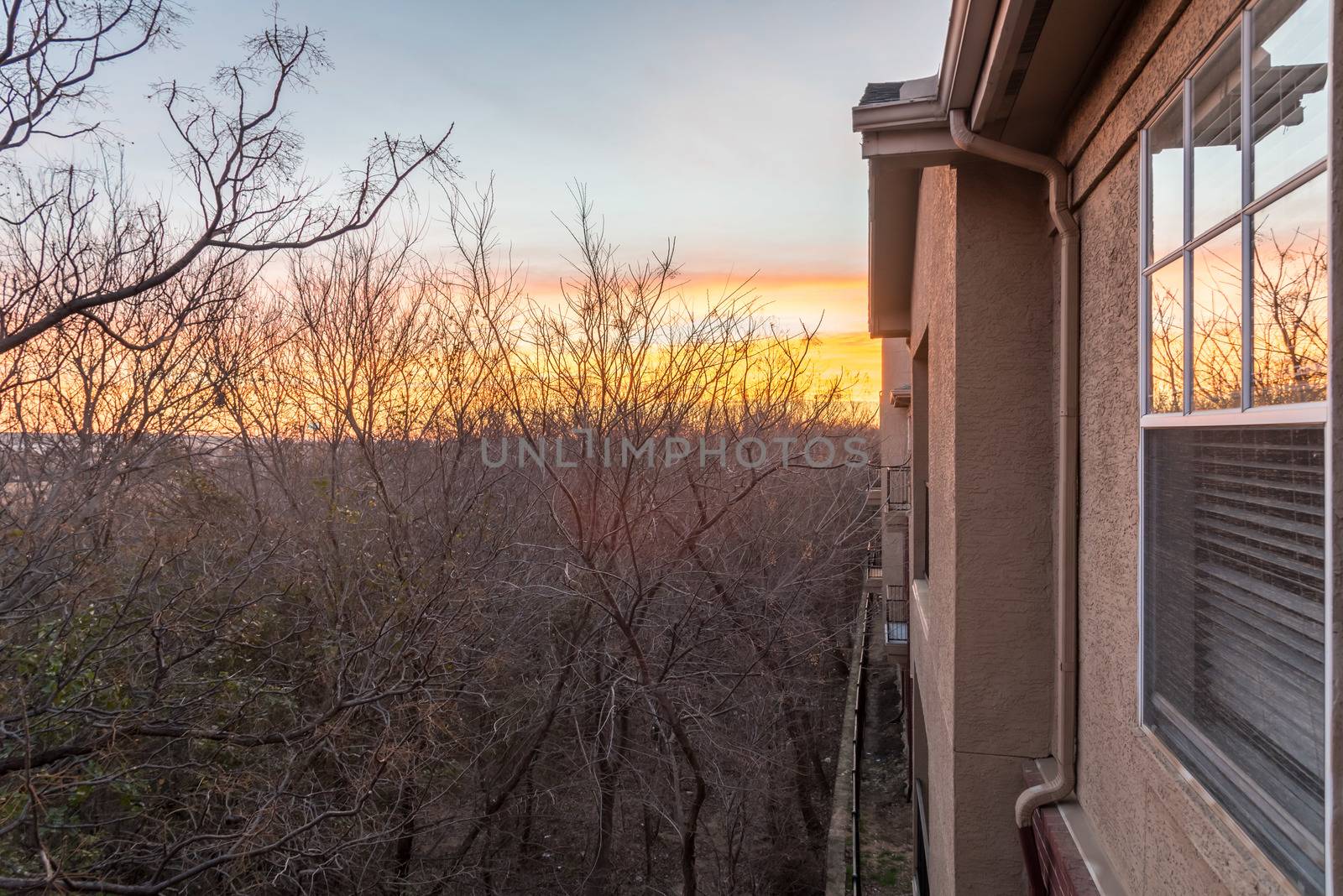 Typical park side apartment complex during winter sunrise with dramatic cloud reflection on windows. Aerial view of apartment building in Texas, America