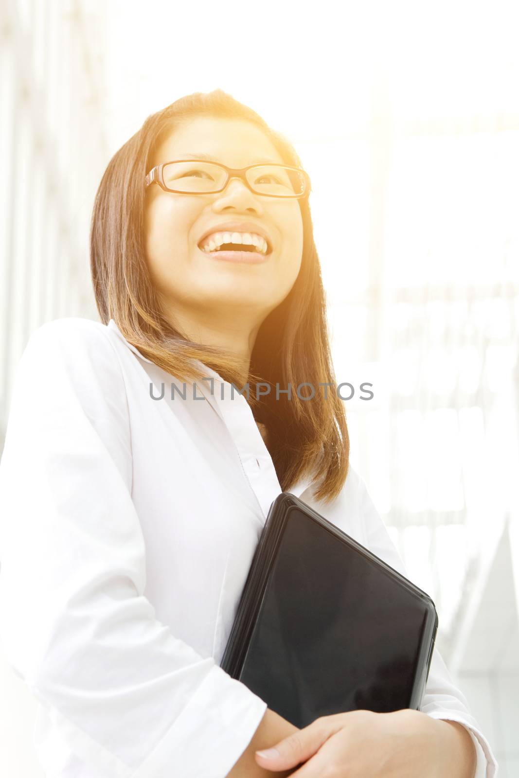 A young Asian woman looking far away to bright light in front of a modern office building.