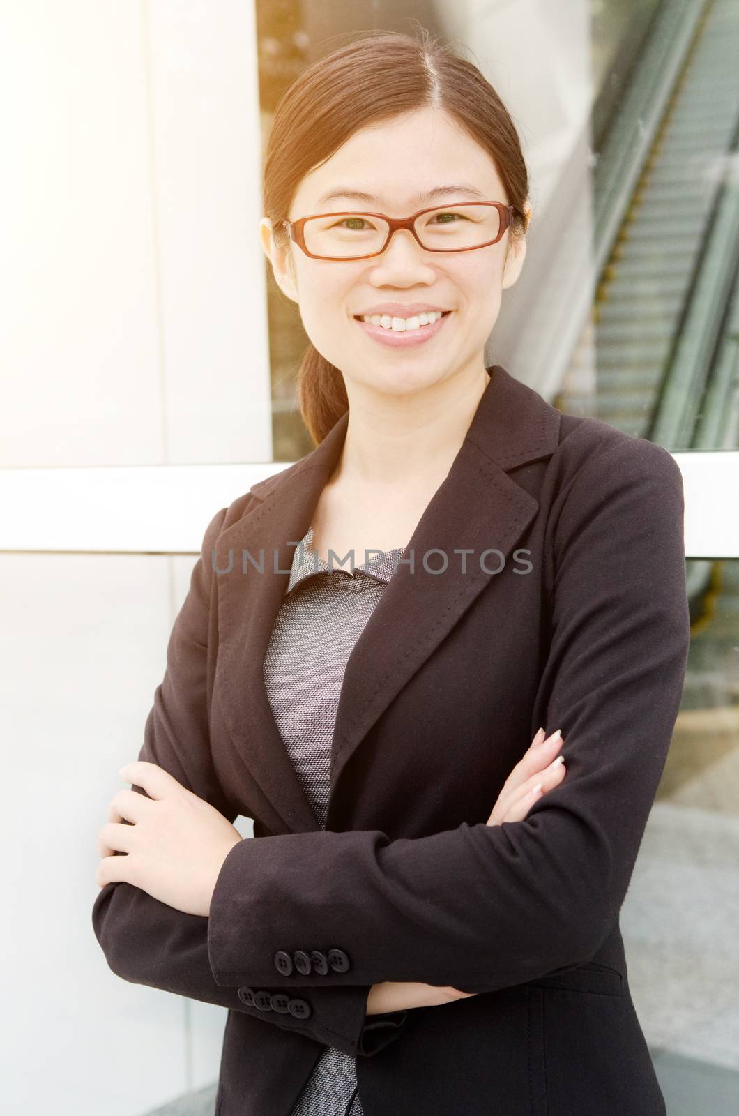 Asian executive arms folded smiles and standing outdoors