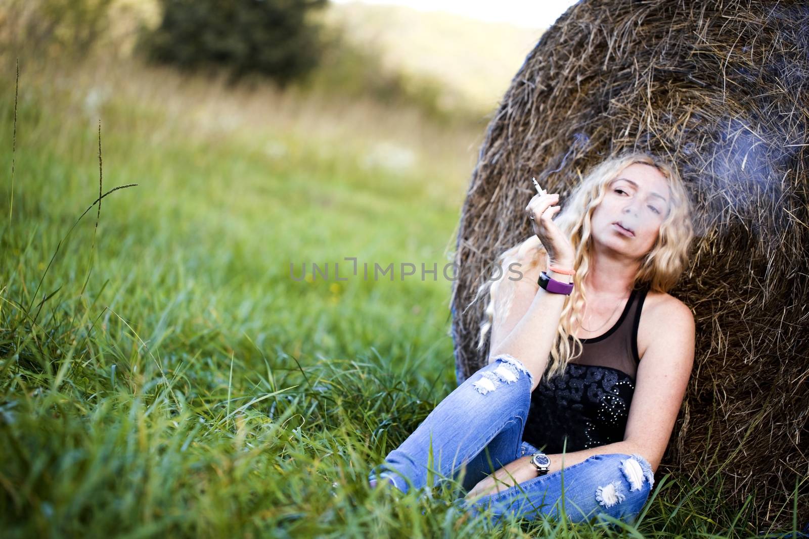 Beautiful young woman near haystacks in the summer field by Anelik