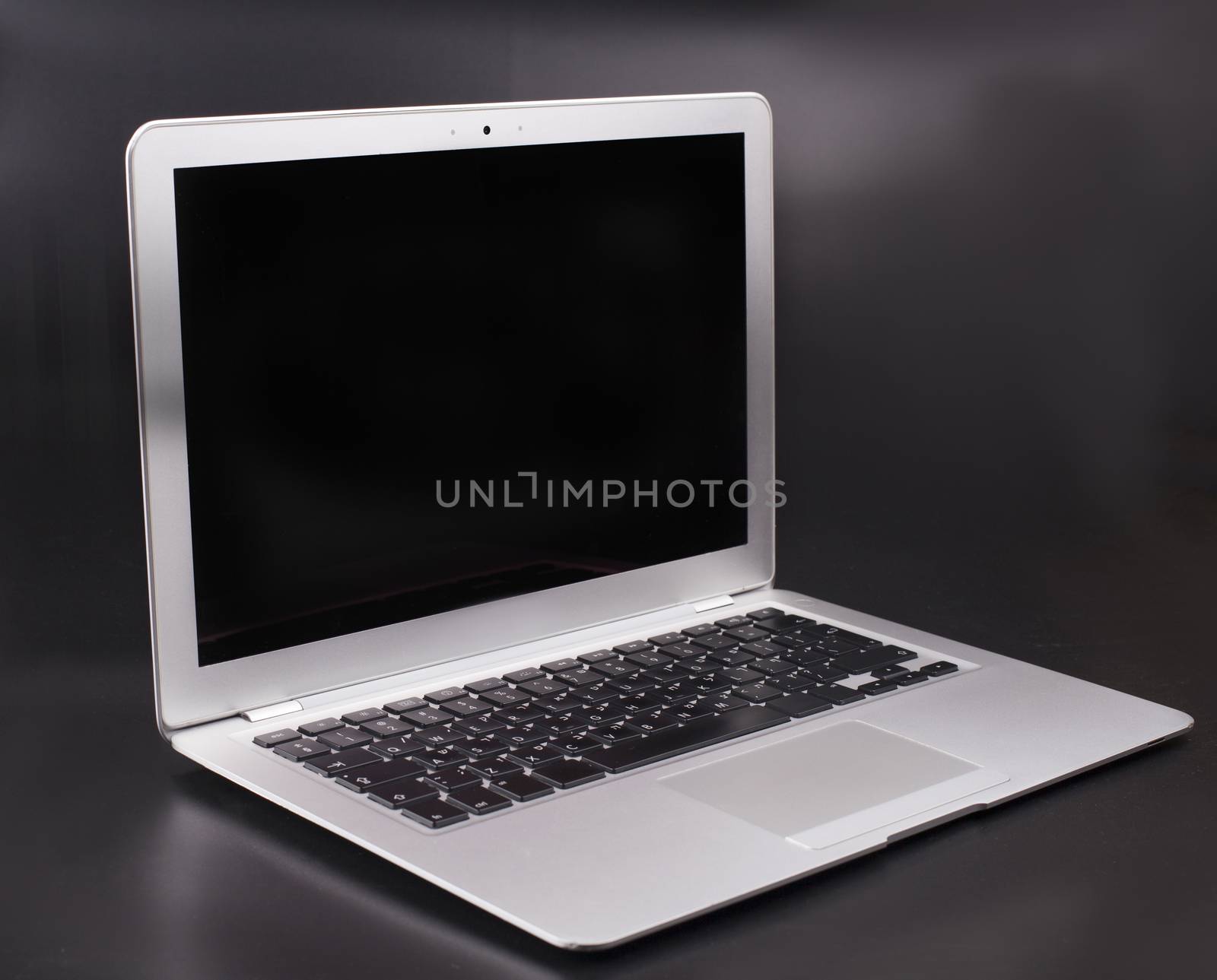 Slim silver color laptop on a dark background with black blank screen