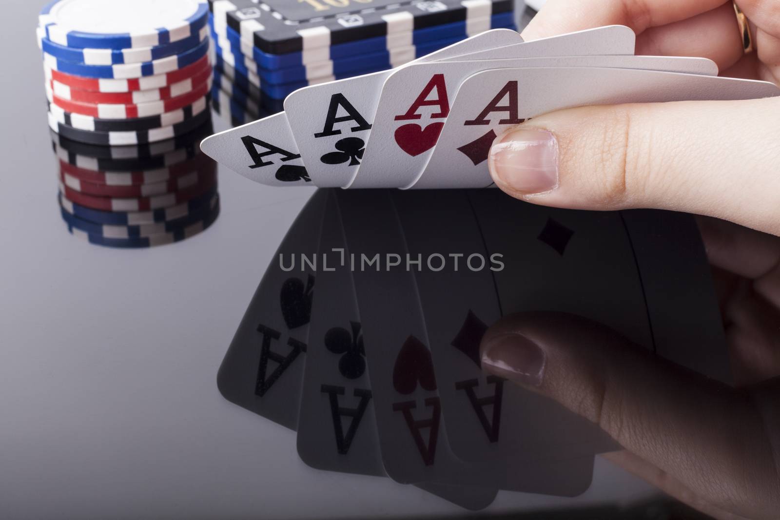 Woman holds aces poker cards with reflection and casino chips in the background
