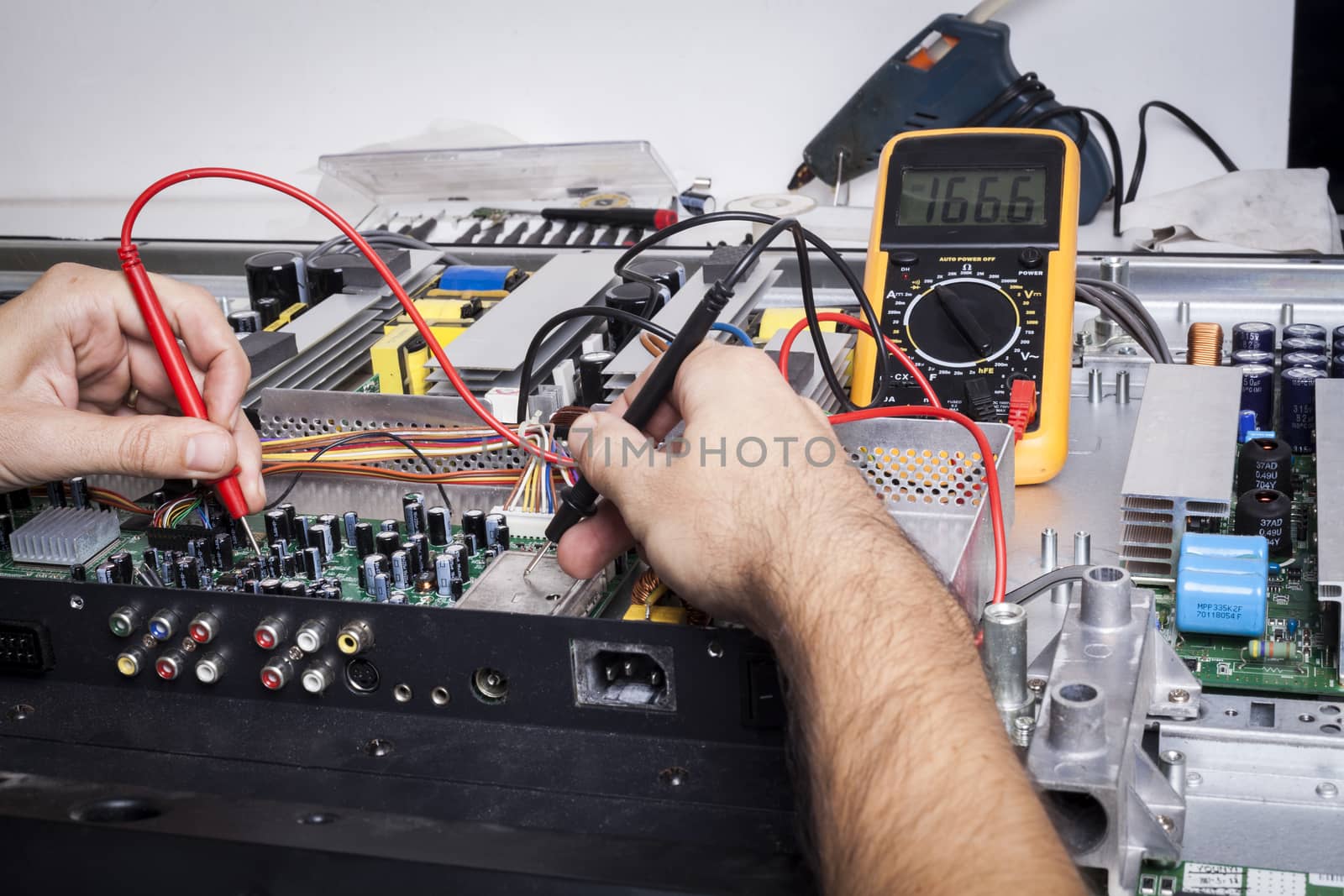Electronics Repair service with red probe and capacitors on electronic board