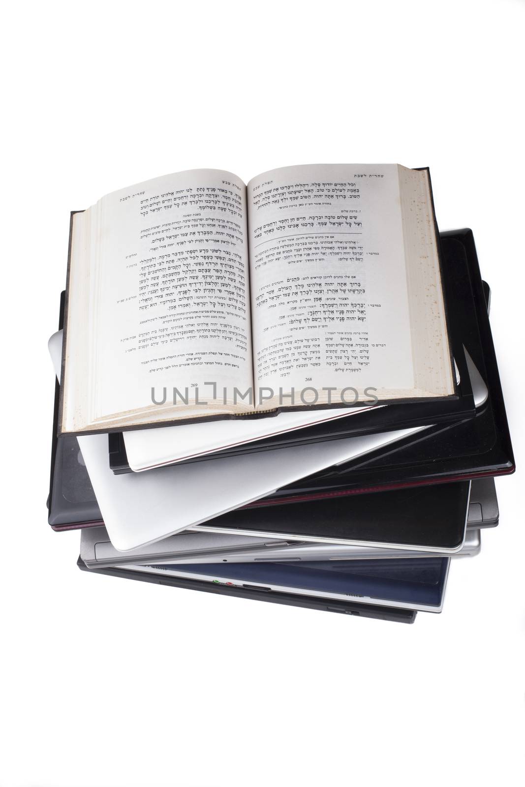 Old Bible in hebrew on top of laptop pile top view isolated on white background