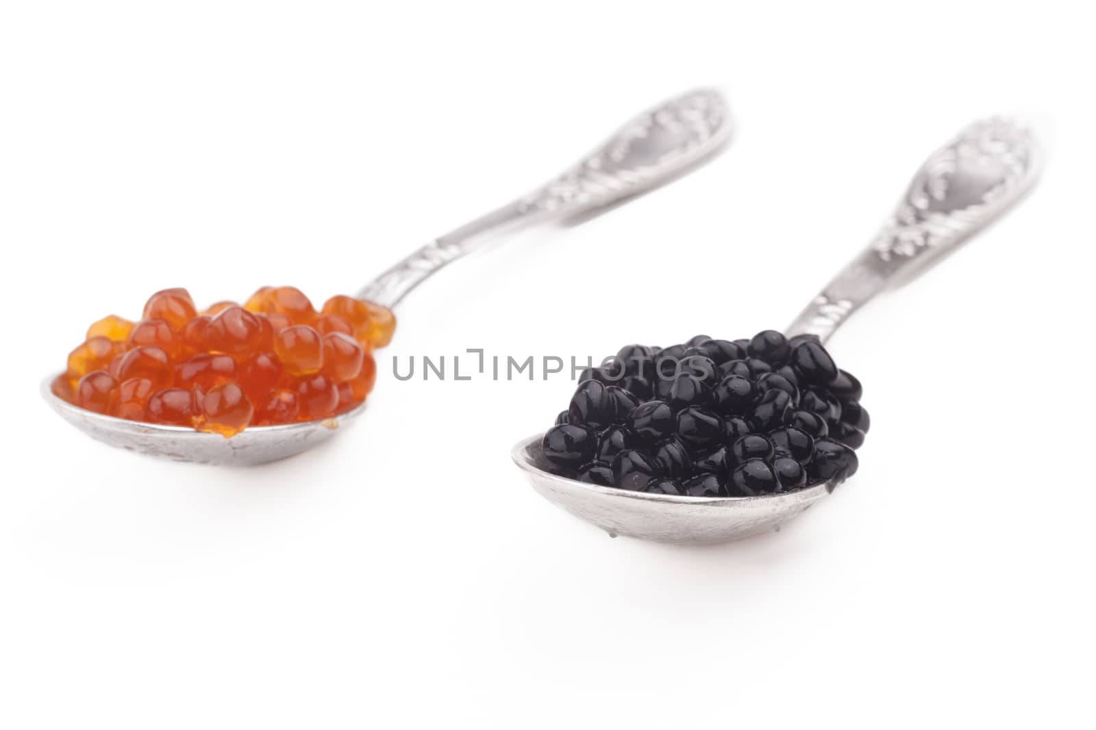 Red and Black caviar beads on silver spoon close-up isolated on white background