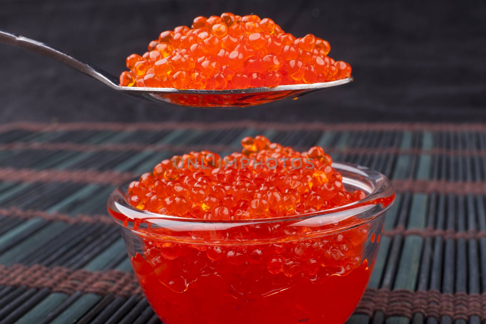 Red caviar on a spoon close-up on dark background