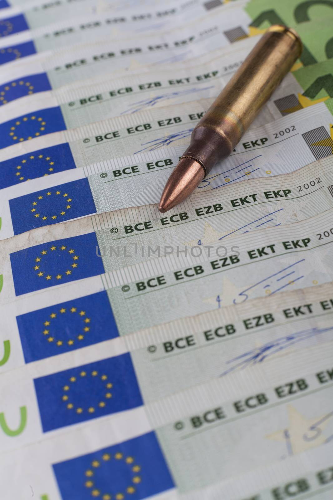 Bullet close-up on green euro banknotes row with european sign