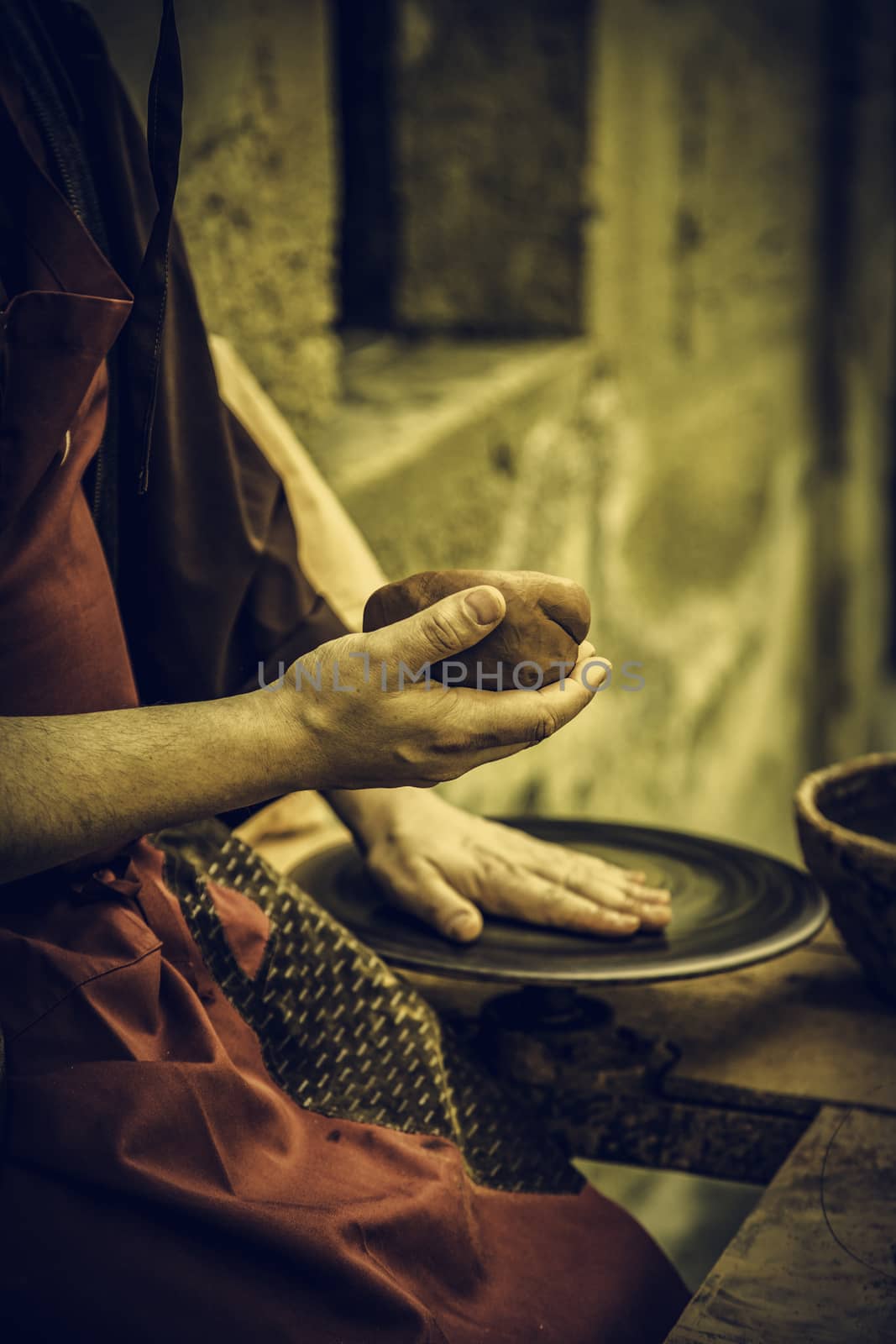 Hands of man working and shaping clay, potter in pottery by esebene