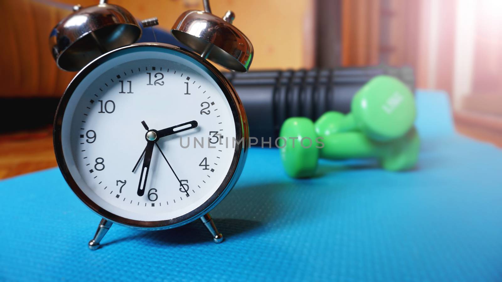 Blue yoga mat, two dumbbells, alarm clock, self-massage roll - time for sport by natali_brill