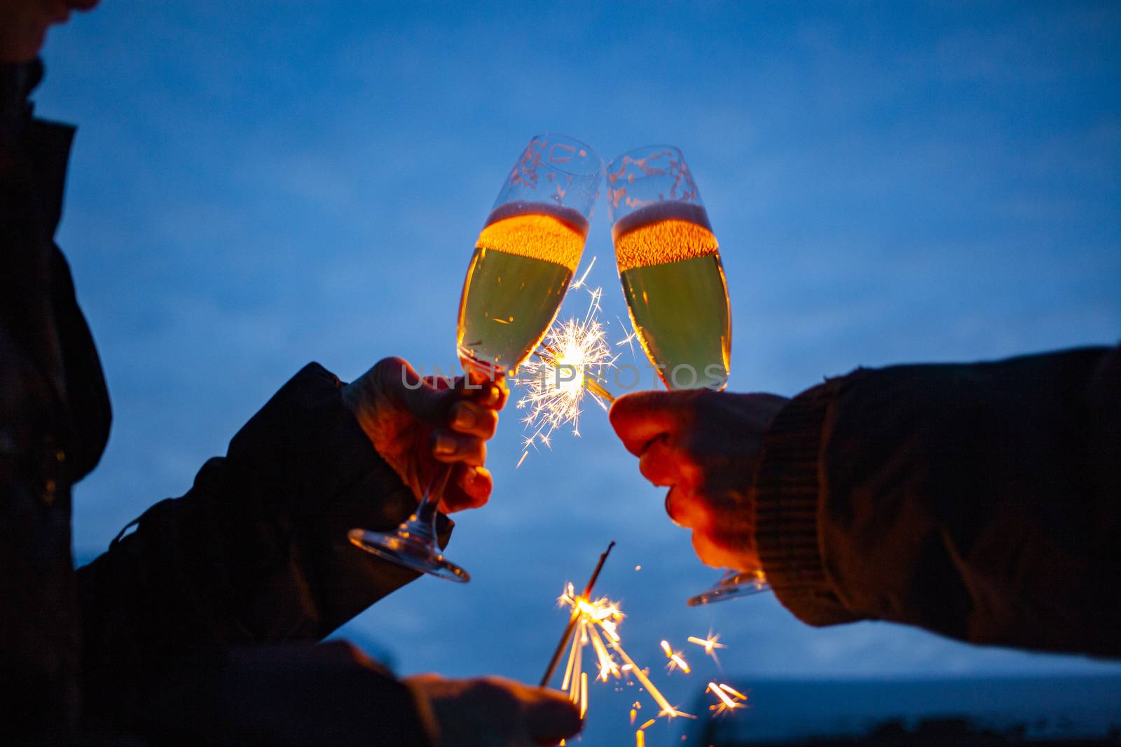 hands of elderly couple holding sparkles and glasses of champagne celebrating New Year