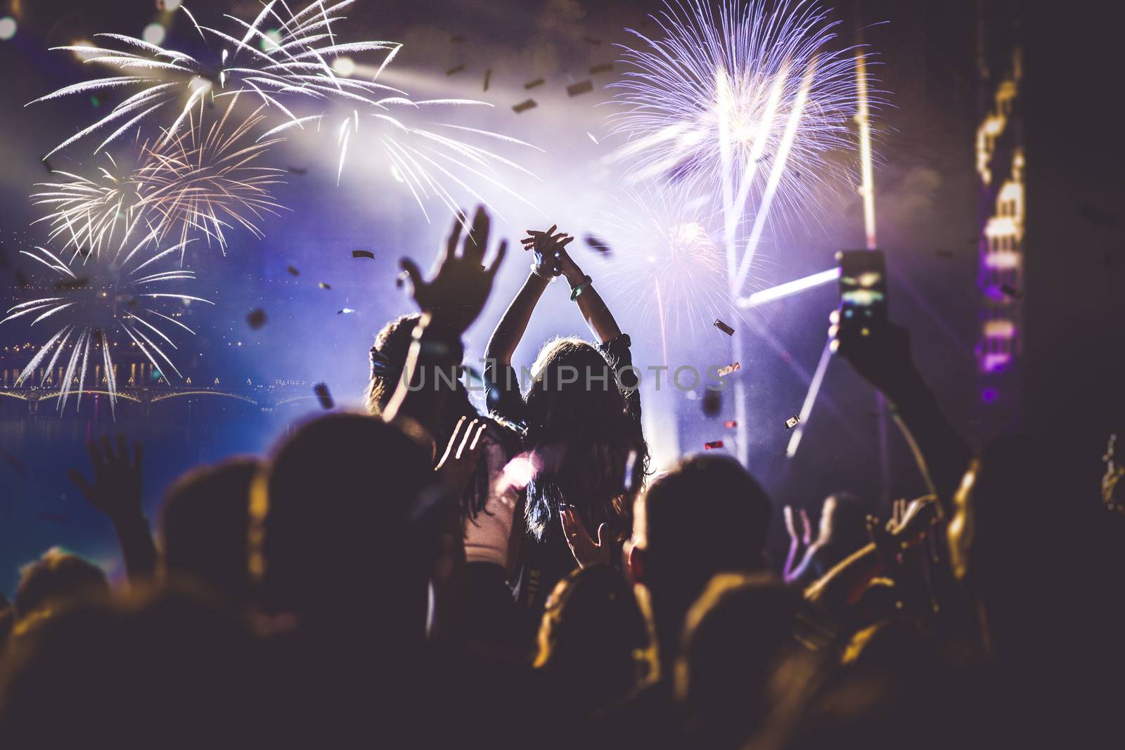 cheering crowd with raised hands and falling confetti at concert - music festival