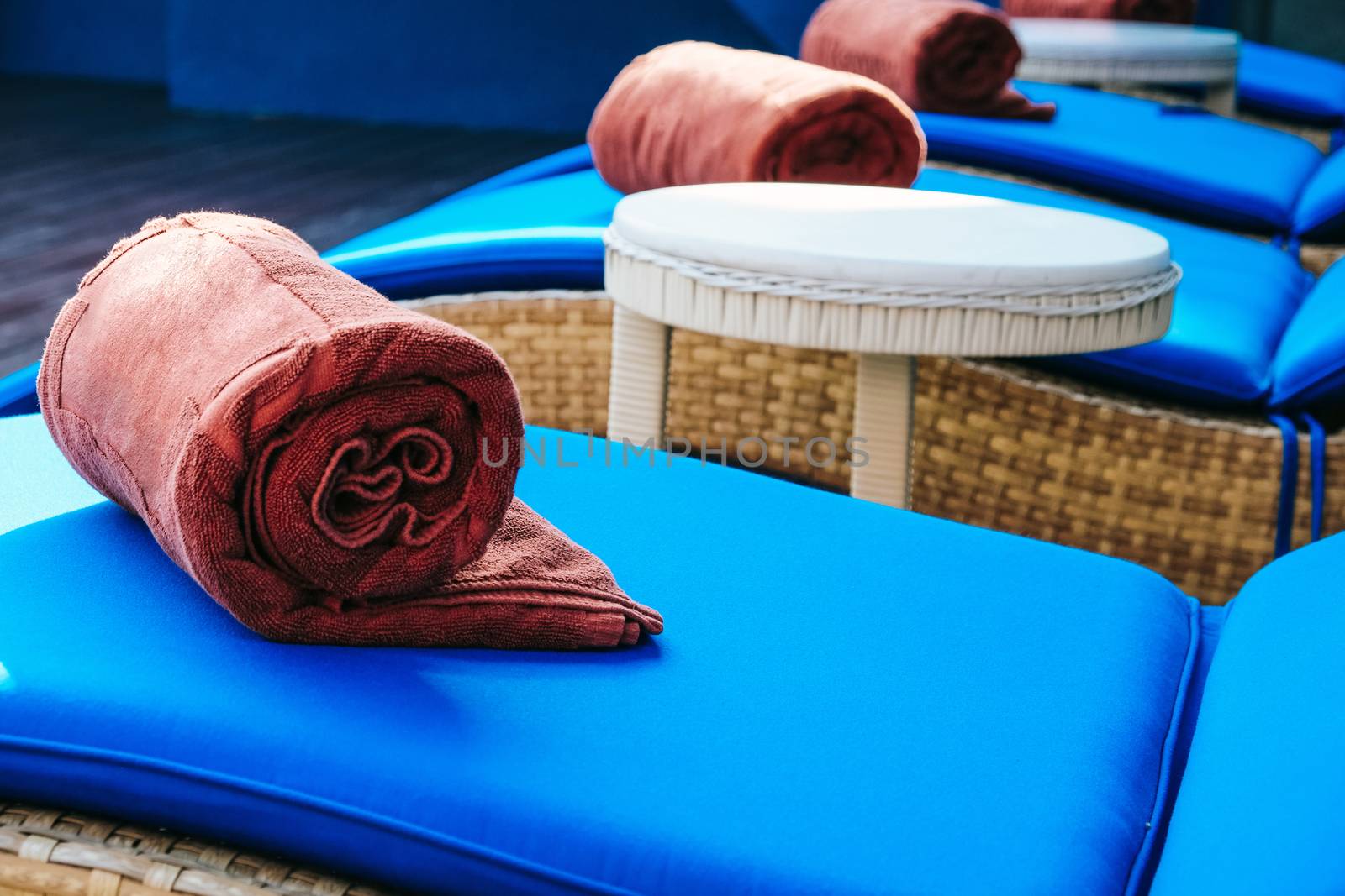 image of Folded towels on lounge chairs beside pool