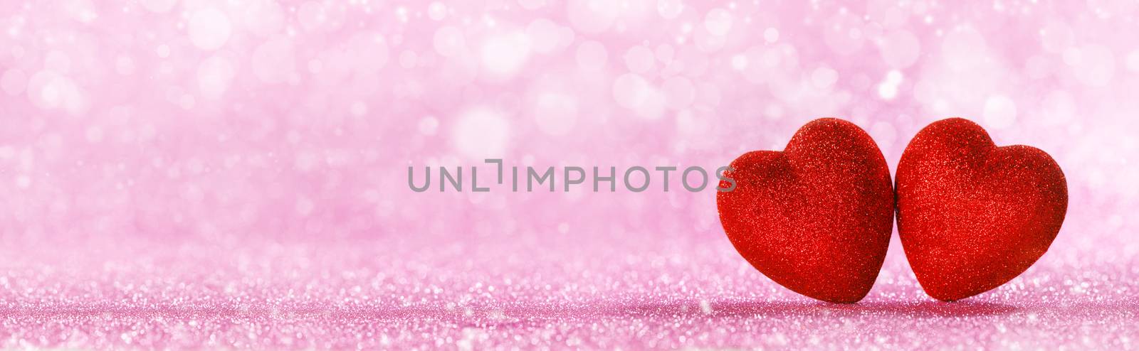 Two red glitter hearts on bright heart lights bokeh background