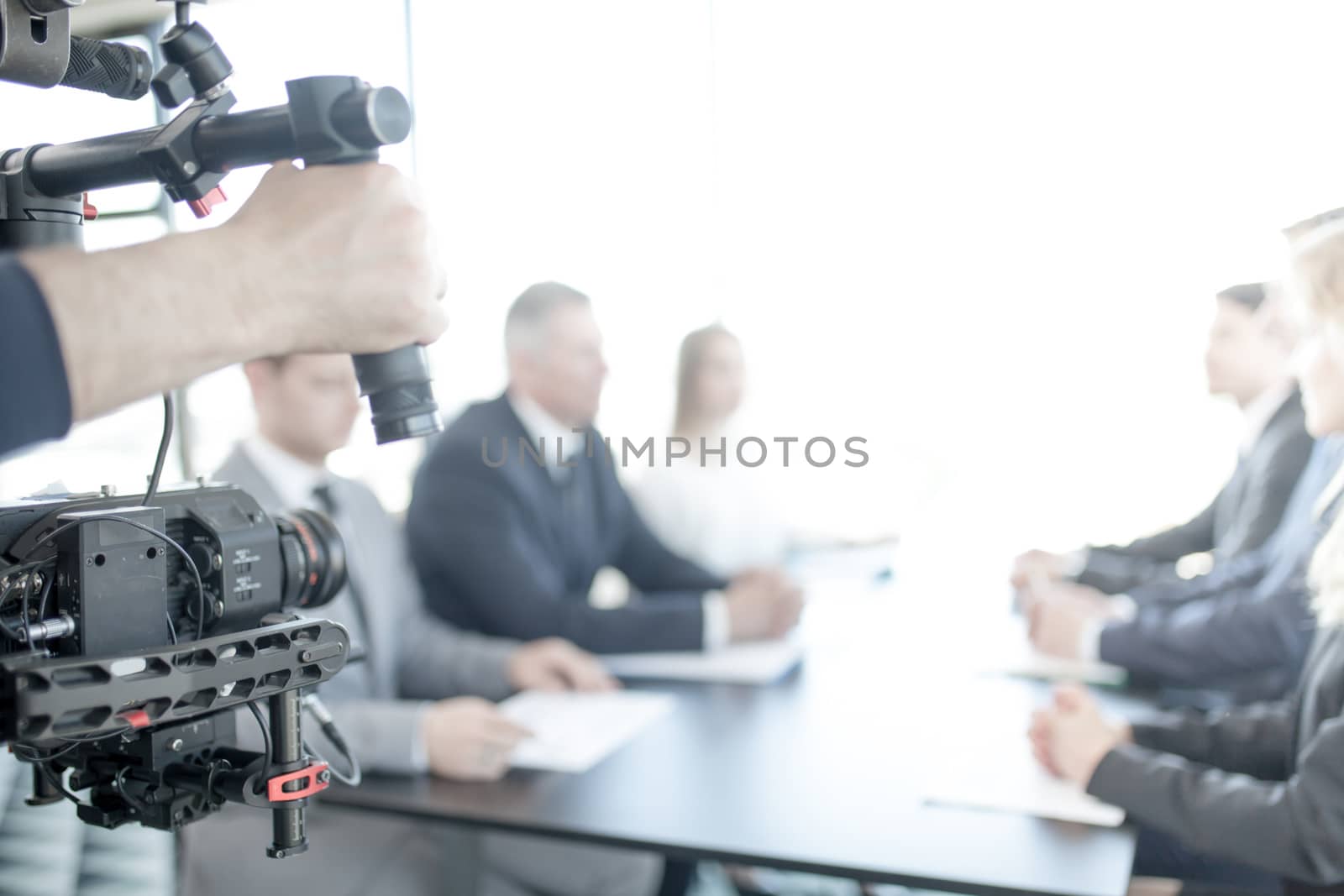 Videographer using steadycam, making video of business people at meeting