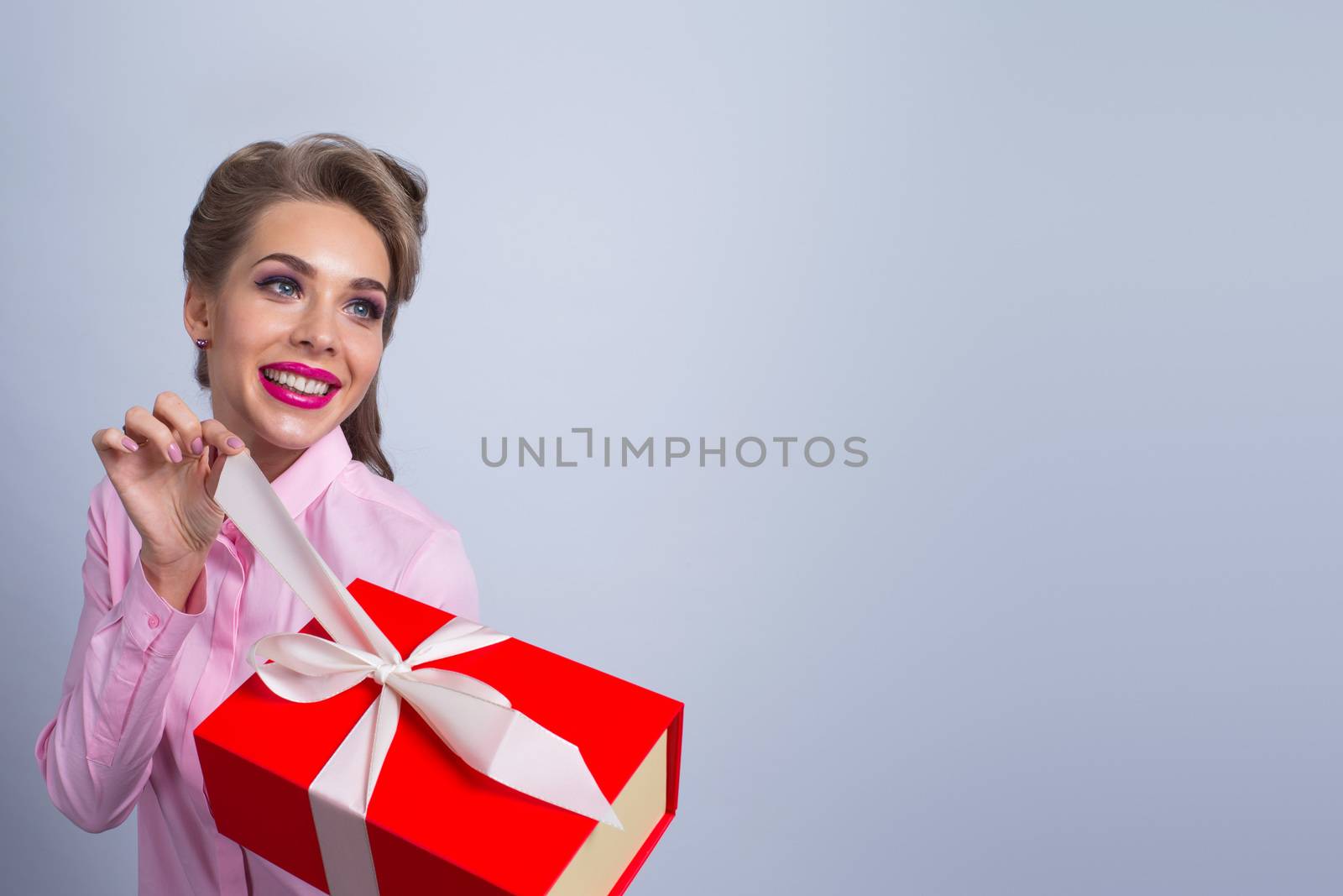 Happy beautiful funny woman open red gift box with white ribbon