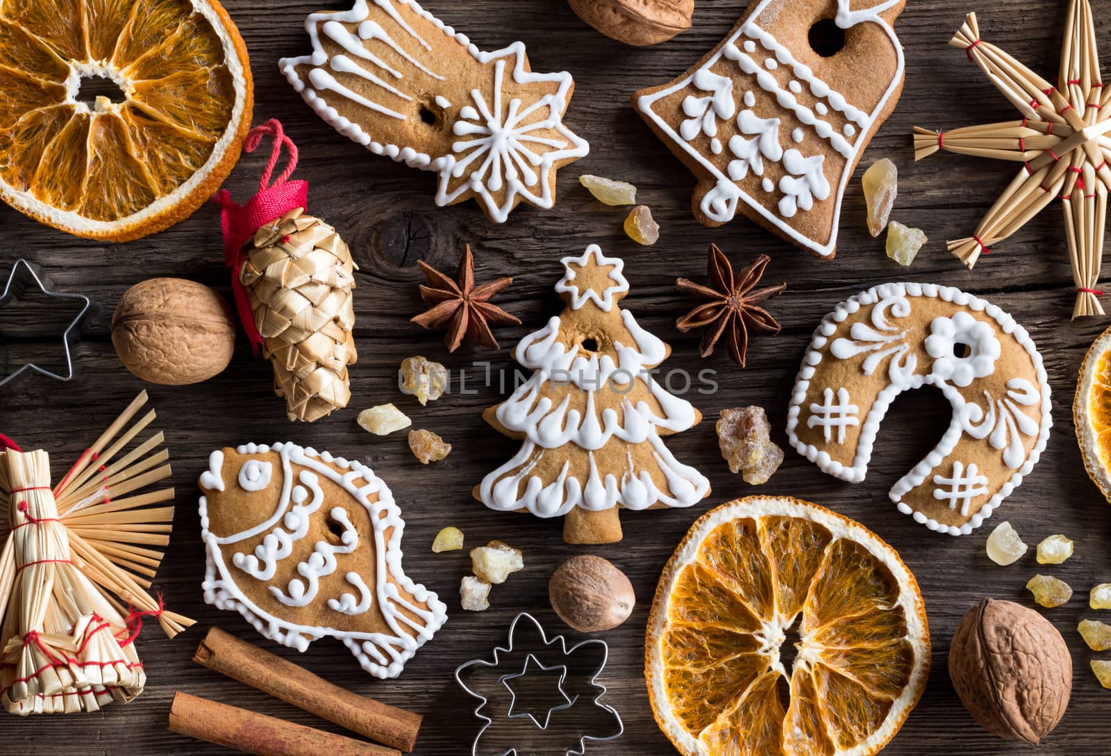 Christmas decoration - gingerbread cookies, straw ornaments, star anise, walnuts, nutmeg, cinnamon, frankincense resin and dried orange slices on a wooden background, top view