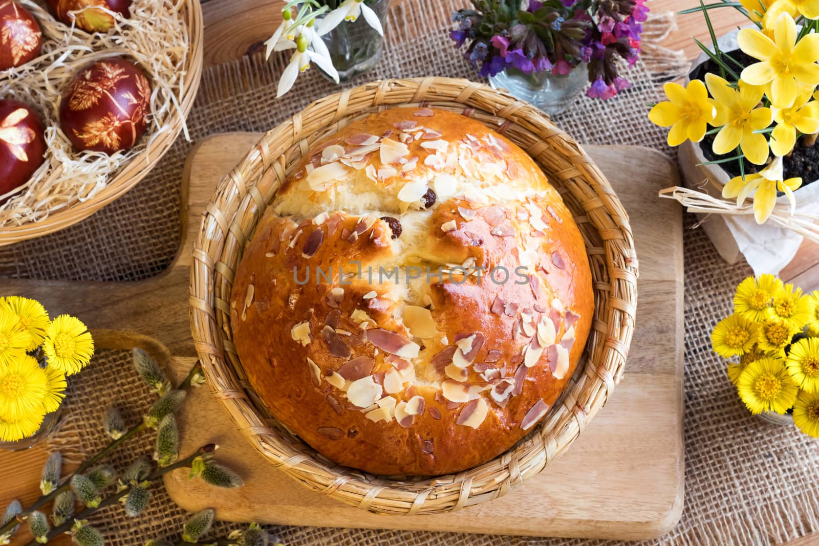 Mazanec, traditional Czech Easter pastry, similar to hot cross bun, with snowdrops, lungwort, coltsfoot, pussy willow, yellow crocuses and easter eggs dyed with onion peels. Top view.