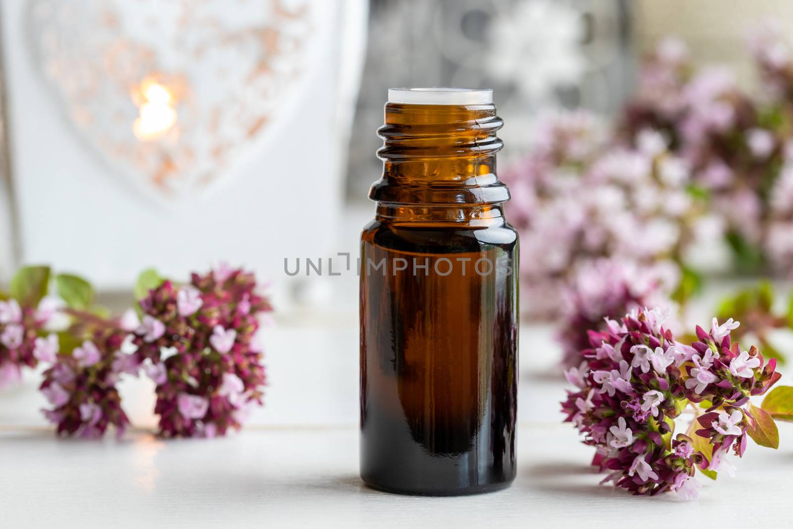 A bottle of essential oil with fresh blooming oregano twigs