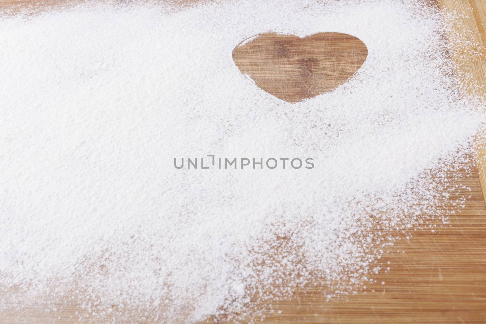 Flour shape heart in a mold on brown wood cutting board