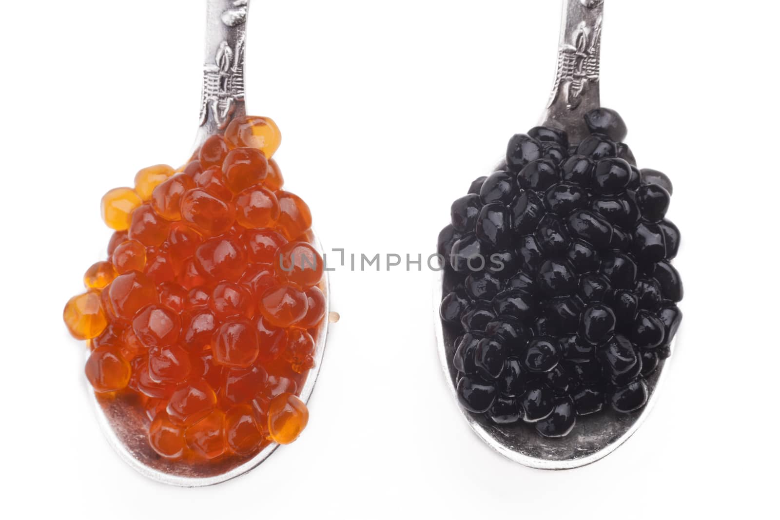 Red and Black caviar beads on two silver spoons close-up isolated on white background