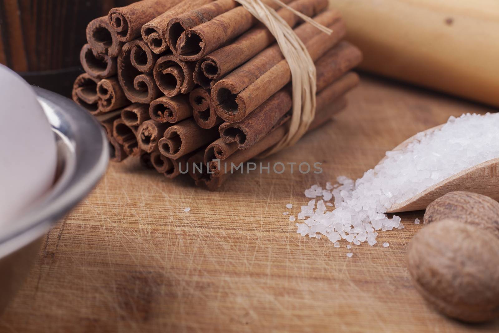 Cinnamon sticks roll on brown wood cutting board