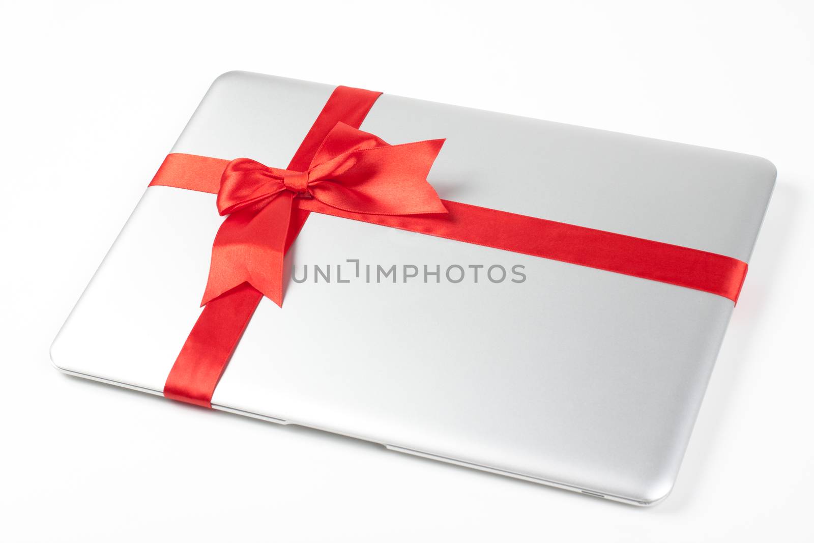 closed silver laptop gift with red ribbon isolated on white background