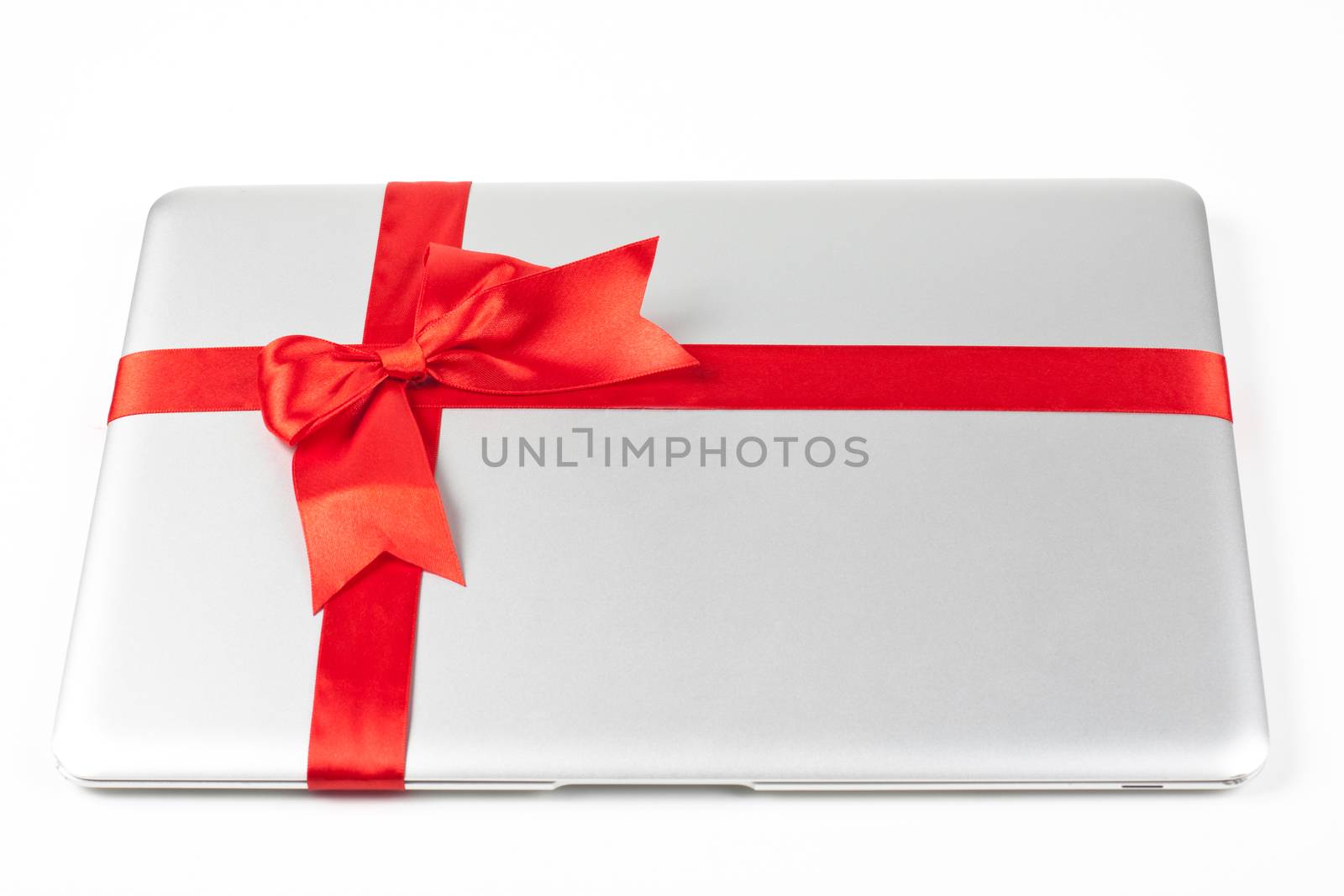 closed silver laptop gift with red ribbon isolated on white background