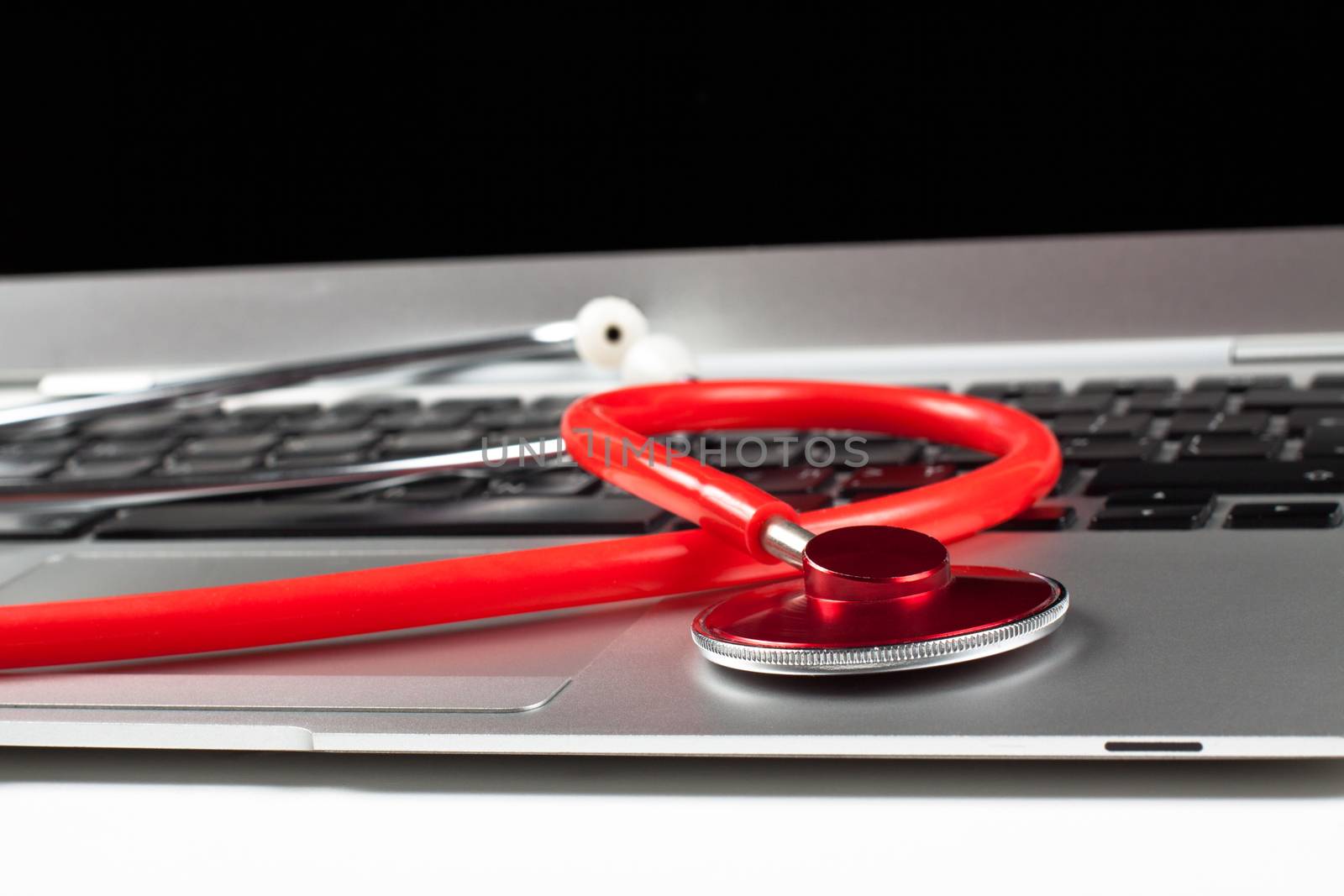 silver laptop diagnosis with black screen and red stethoscope closeup focus on the stethoscope