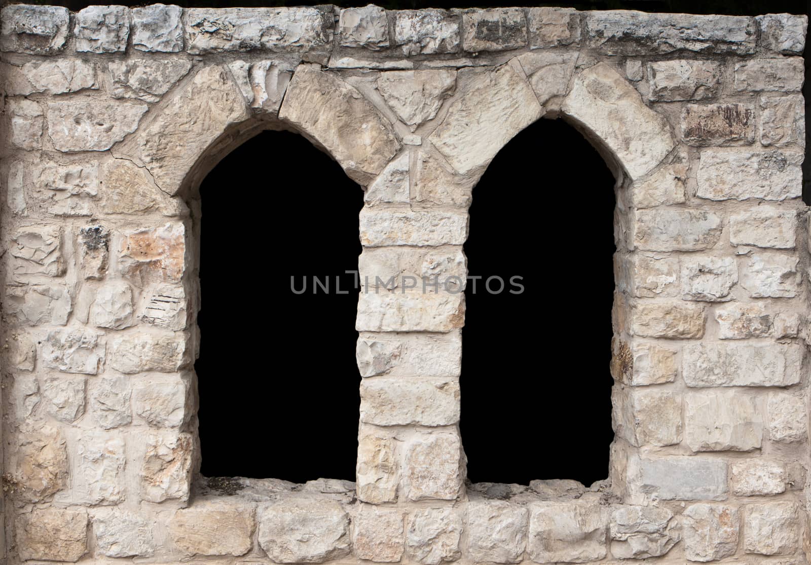 two ancient stone windows with arches and black filling
