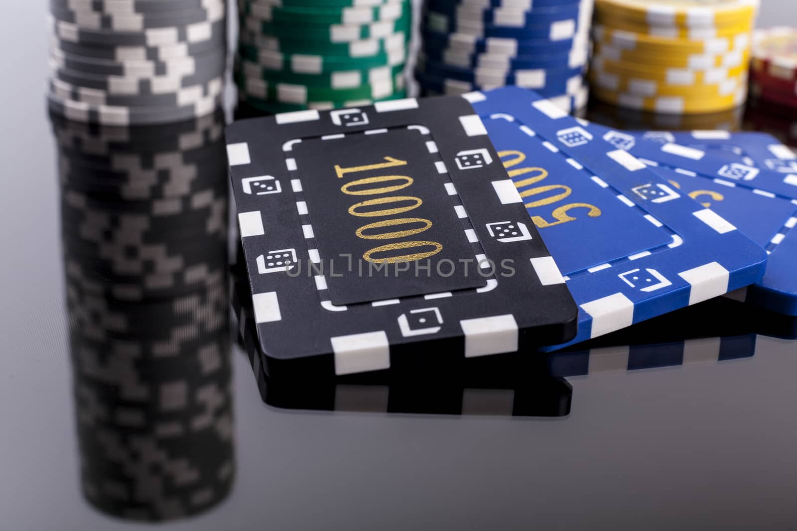 Several Casino chips on a table with reflection