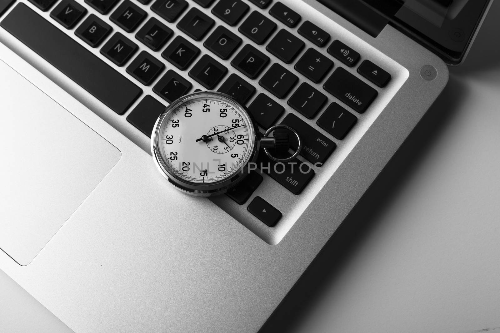 silver laptop with stopwatch on he keyboard closeup 