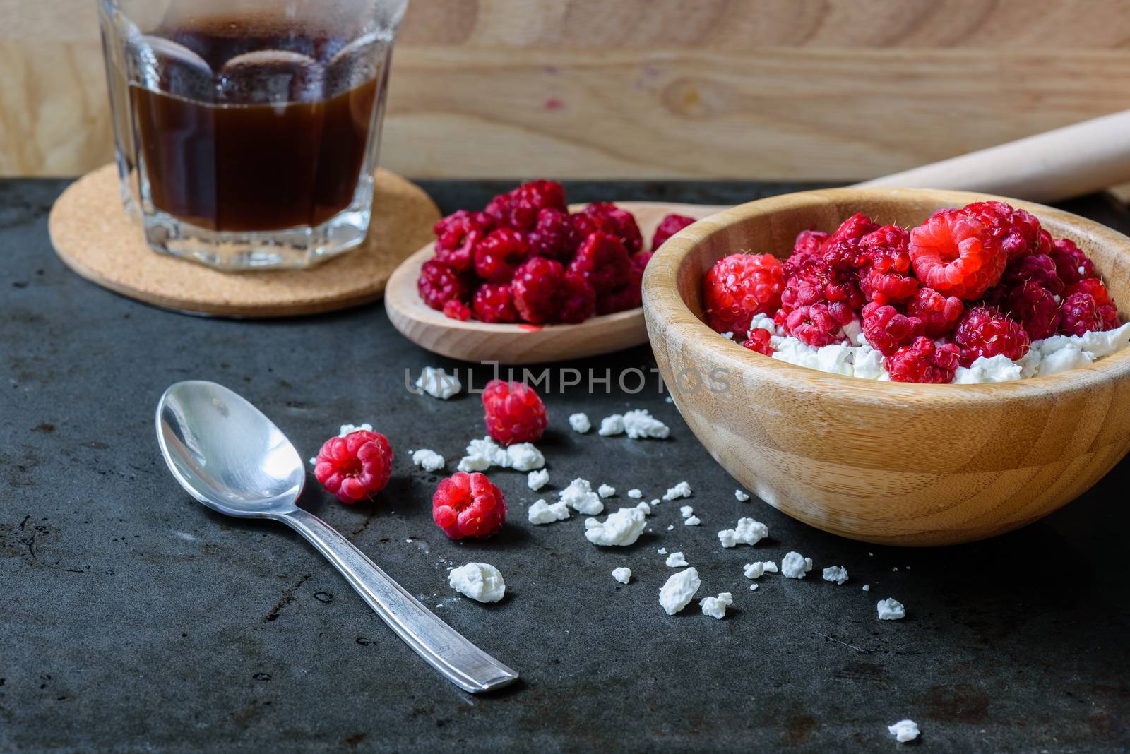 Sweet breakfast with cottage cheese, raspberries and cup of coffee. Scattered berries and grains of curd