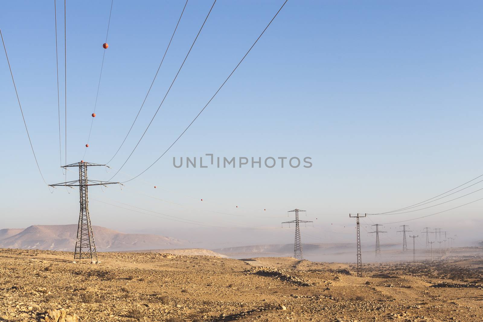 Electricity poles in the desert with mountains and fog in the valley