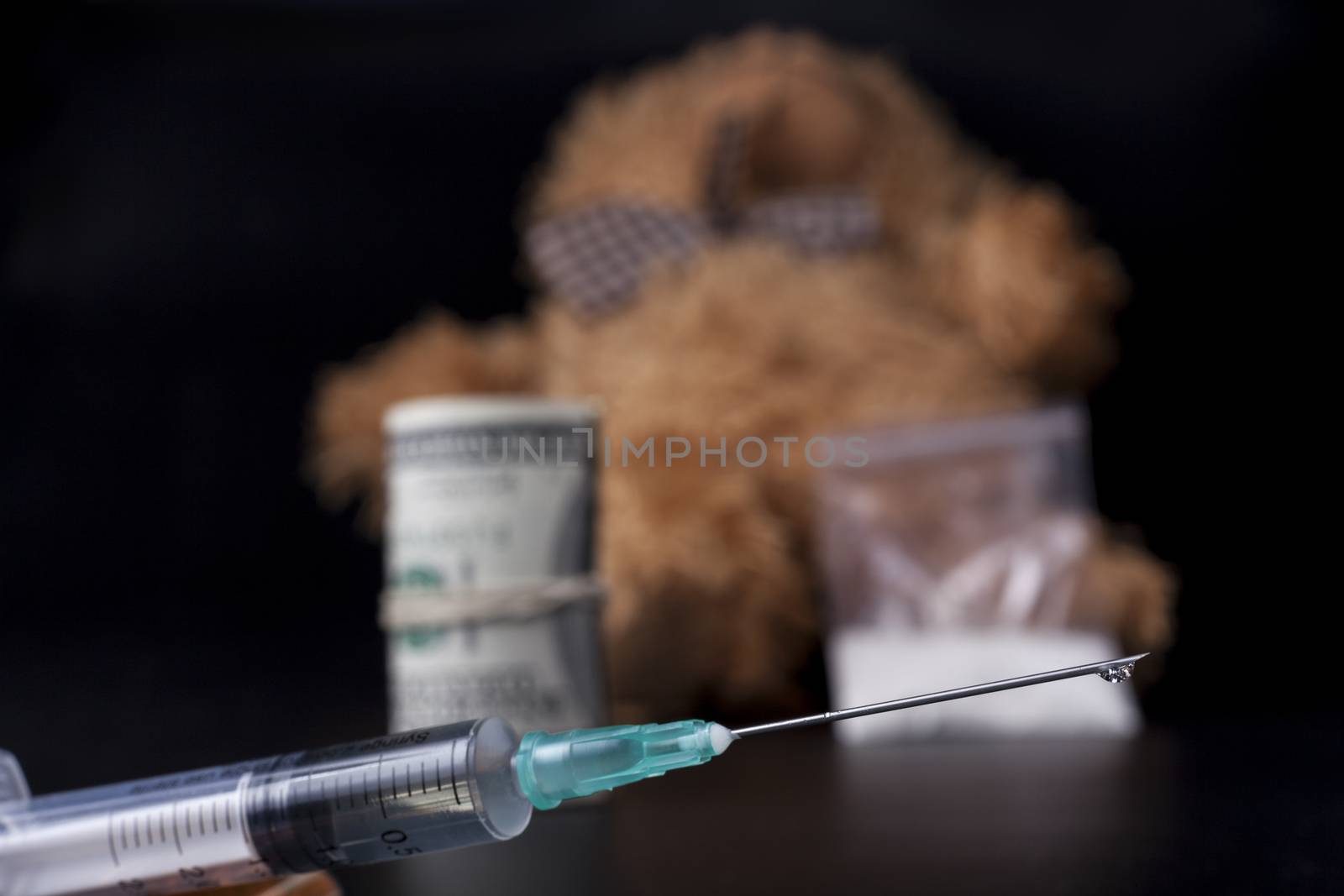 Drug drop syringe closeup with taddy bear in the background