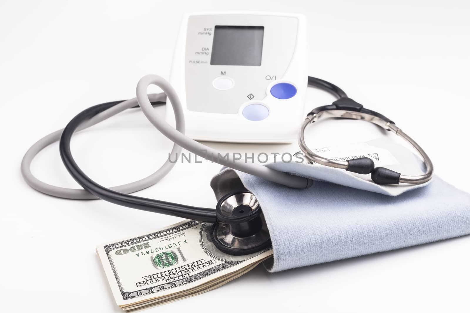 Electronic blood pressure meter with dollar banknotes and stethoscope isolated on white background