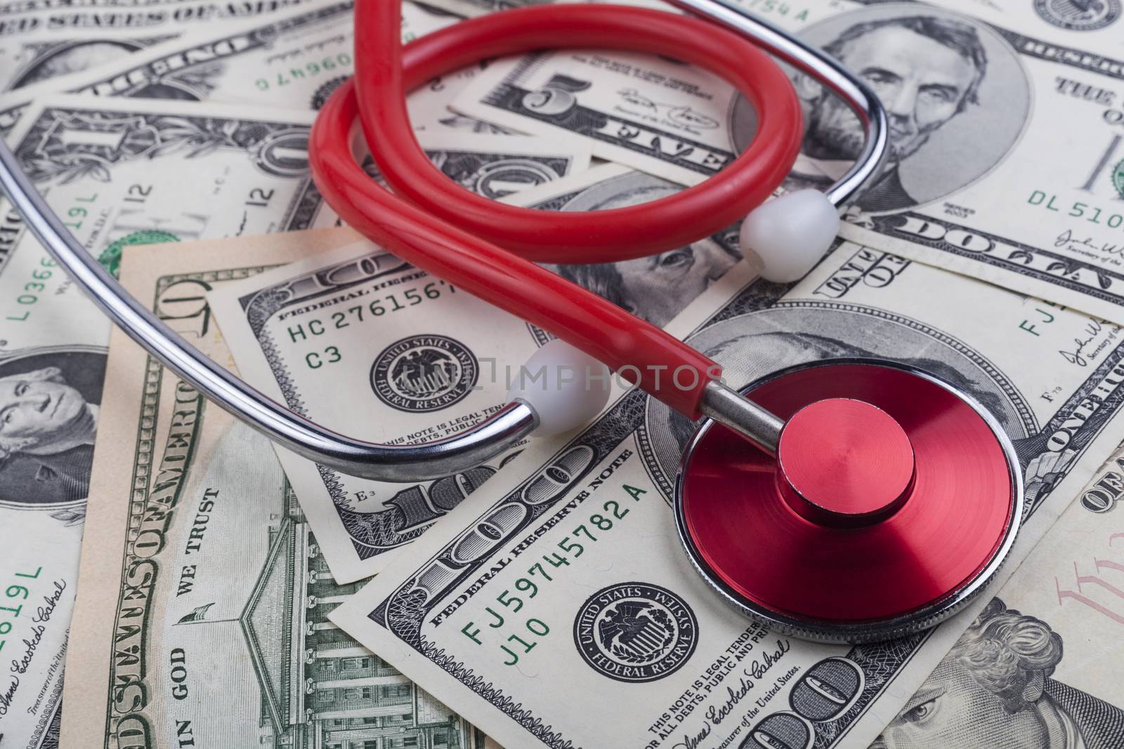 Red stethoscope close-up on top of Dollar banknotes