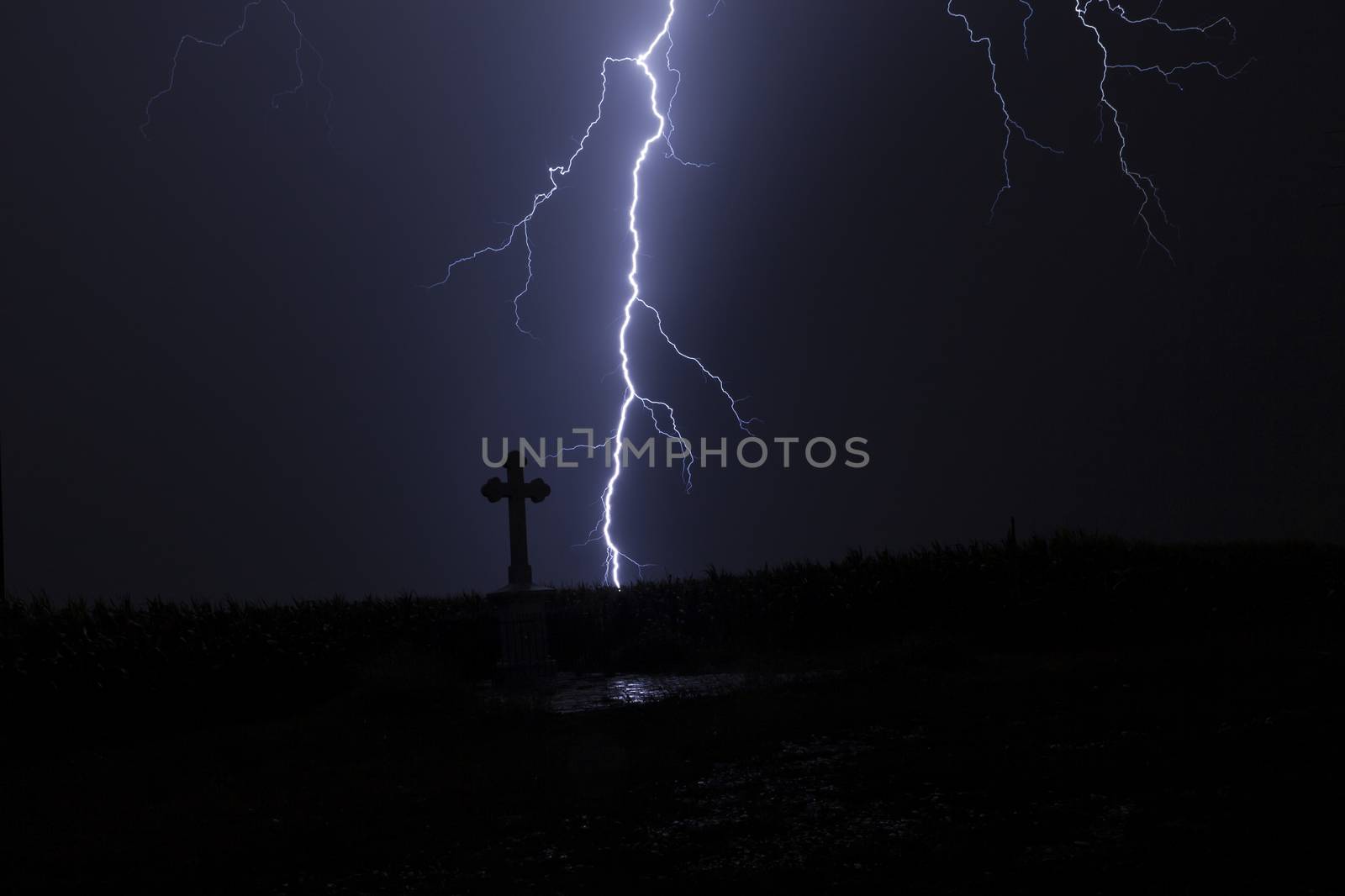 Lightning in a storm with a cross and reflection of the lightning